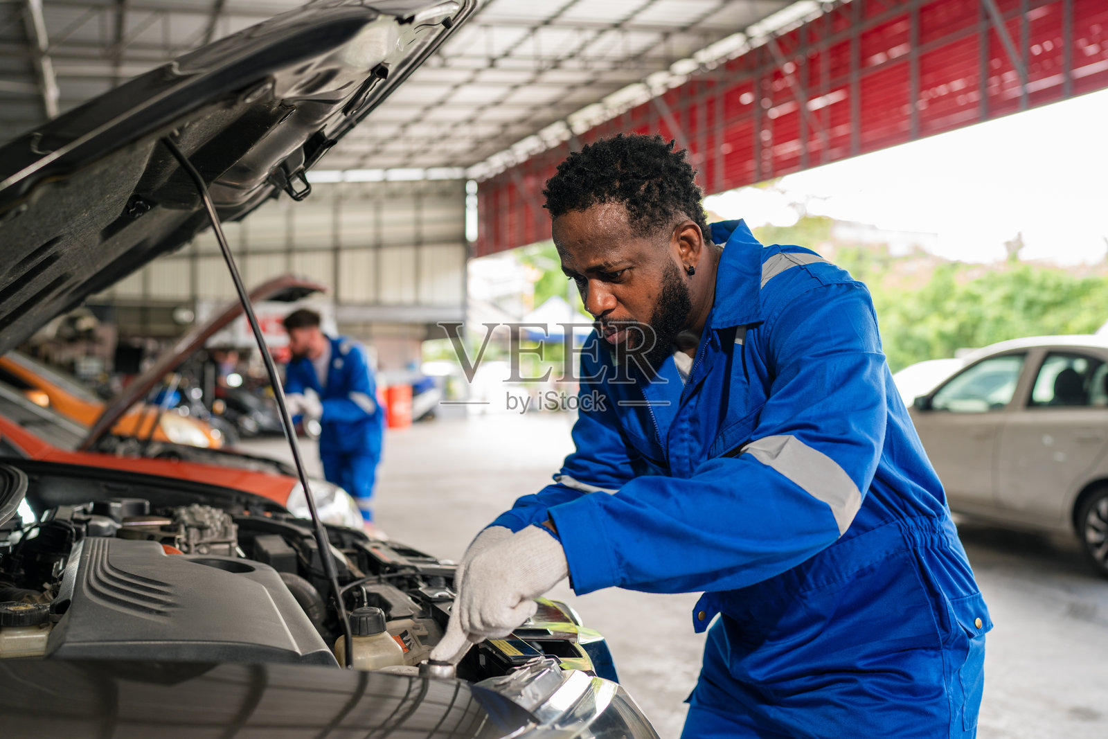汽车修理店的汽车机械师正在检查和修理汽车发动机。照片摄影图片