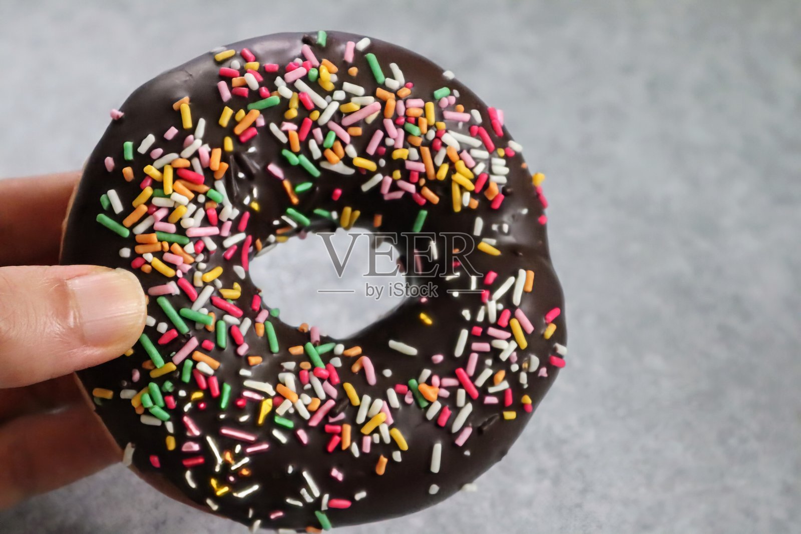 手握五彩缤纷的甜甜圈照片摄影图片