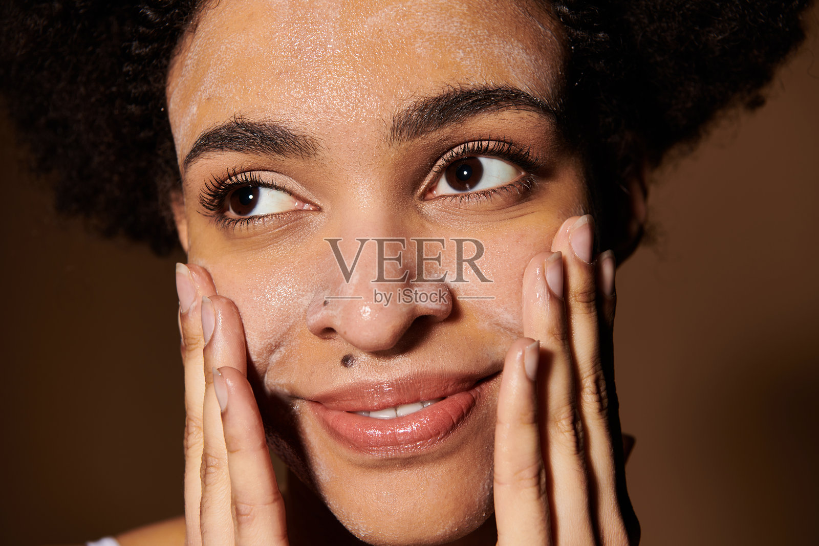 年轻美丽的女性在宁静的环境中微笑着涂抹面部清洁剂照片摄影图片