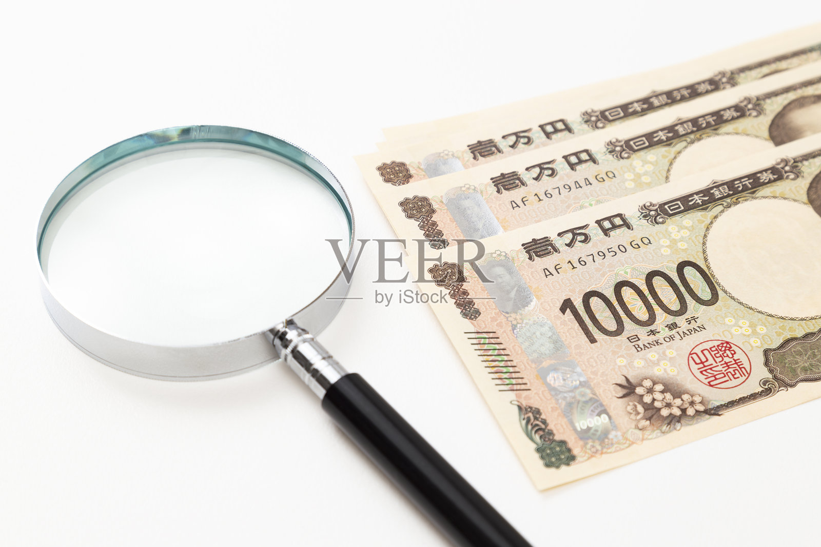 白色背景上的一万元纸币和放大镜。照片摄影图片