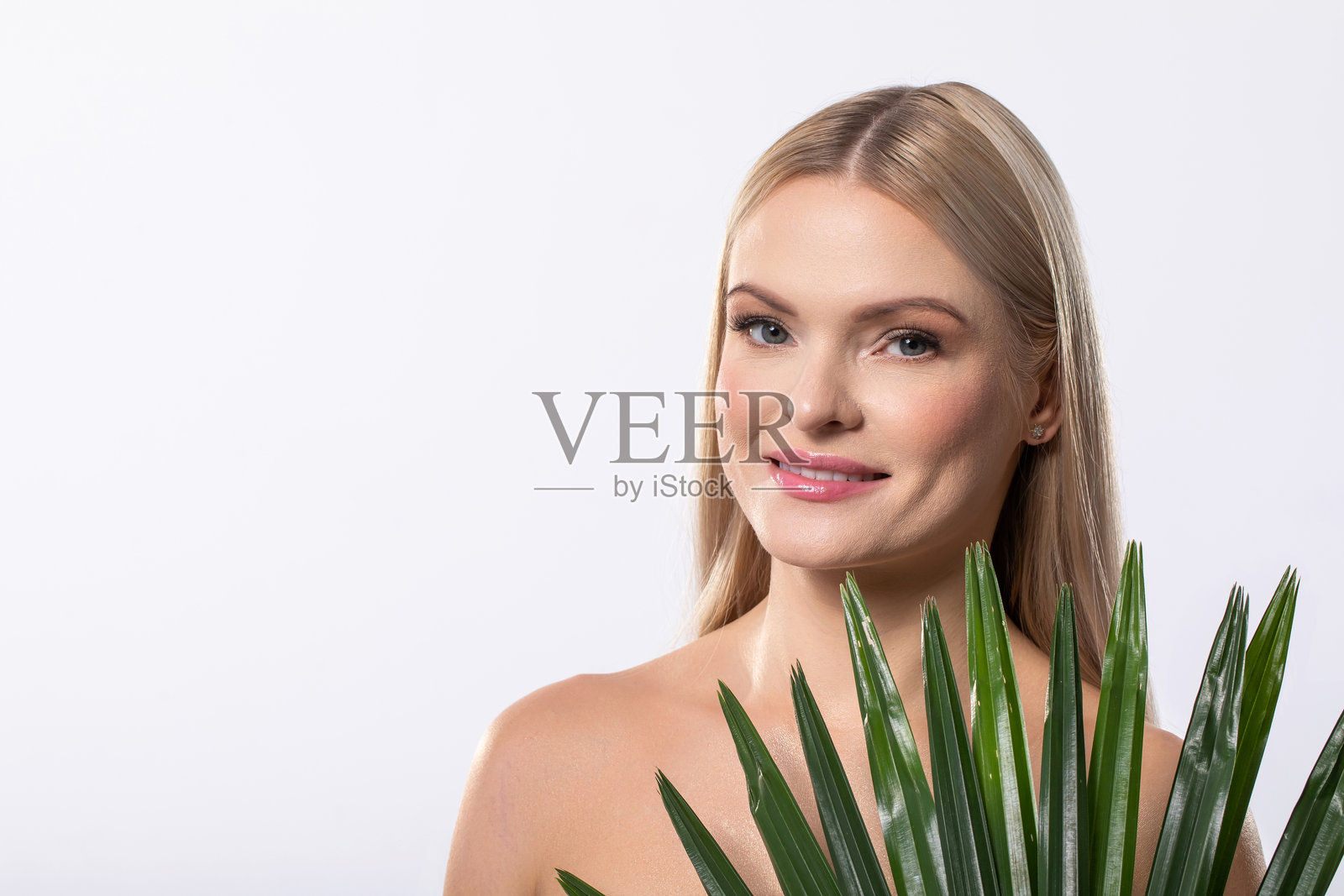 一位惊艳的美丽女性在明亮的工作室中优雅地与热带植物摆姿势照片摄影图片