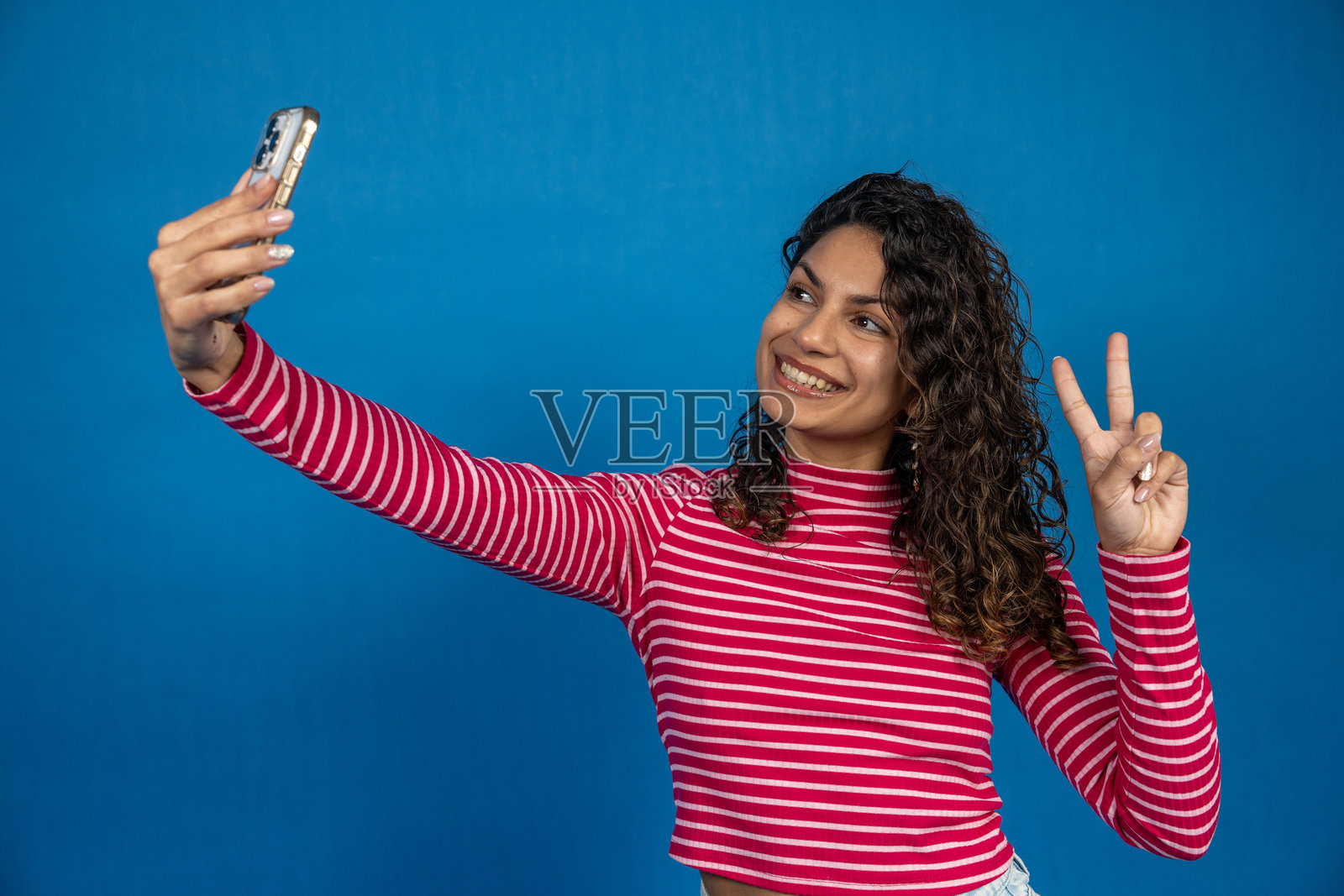 年轻女性用智能手机自拍并做出和平手势照片摄影图片