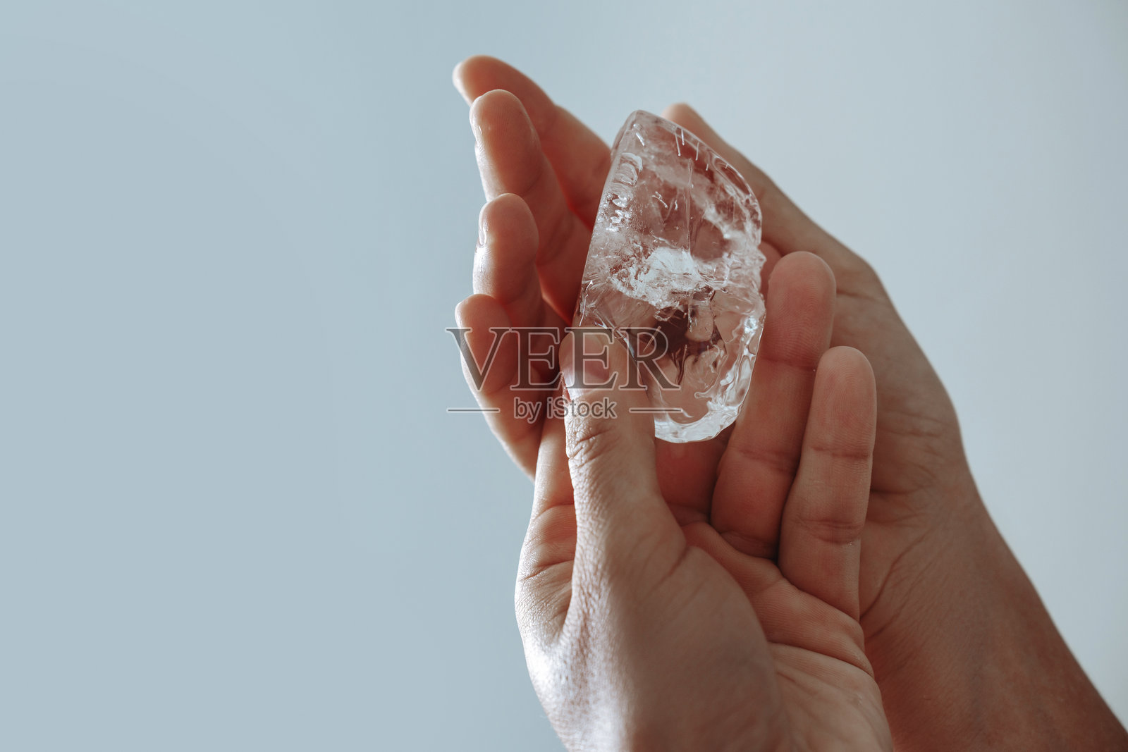 特写镜头下的手轻轻握住一块透明的冰块照片摄影图片