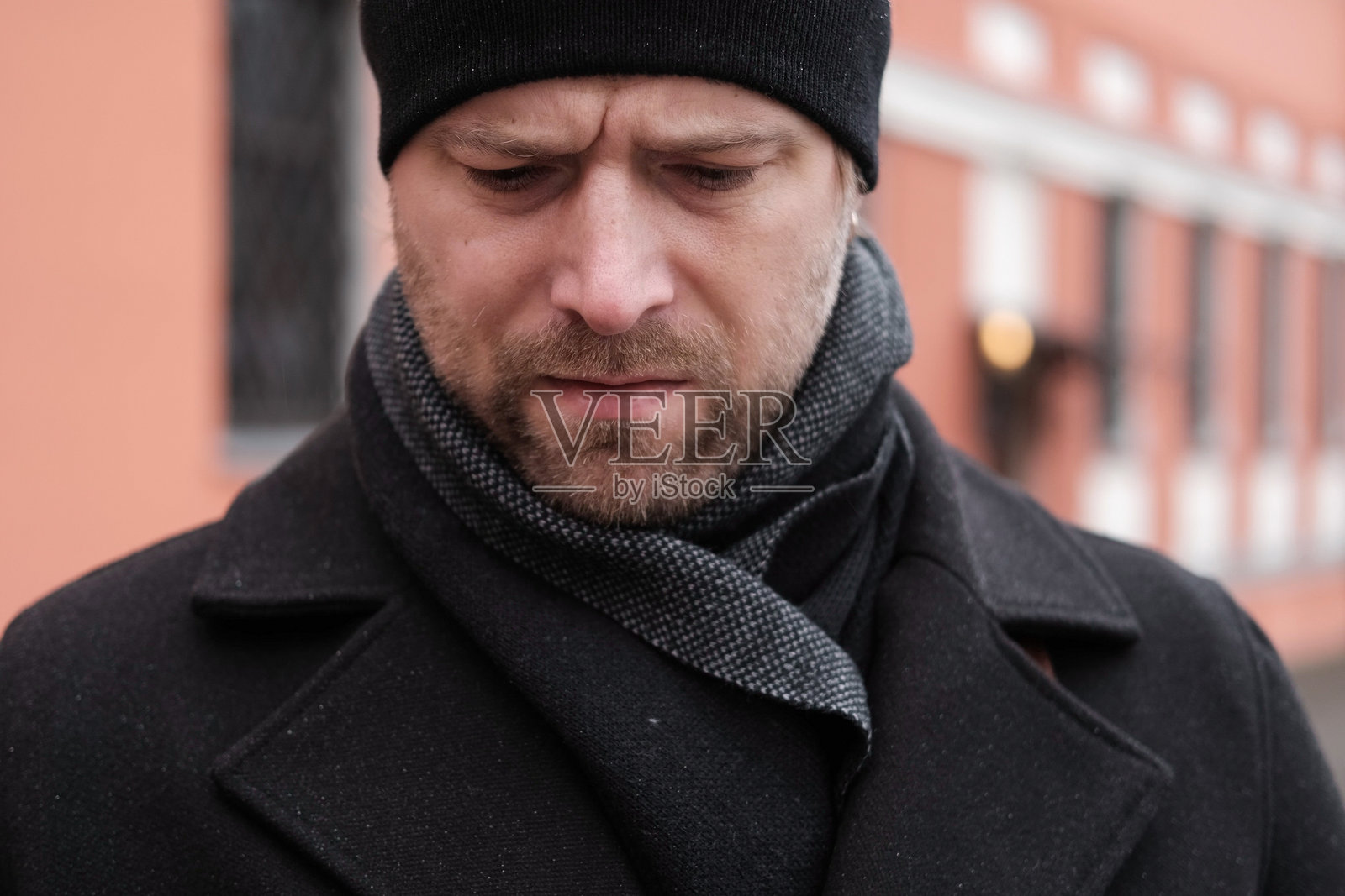 身穿黑色外套、手提棕色皮包的帅气男士在城市街道上走着,手中拿着手机。时尚的中年男性在城市街道上使用智能手机。商人正在前往工作。照片摄影图片