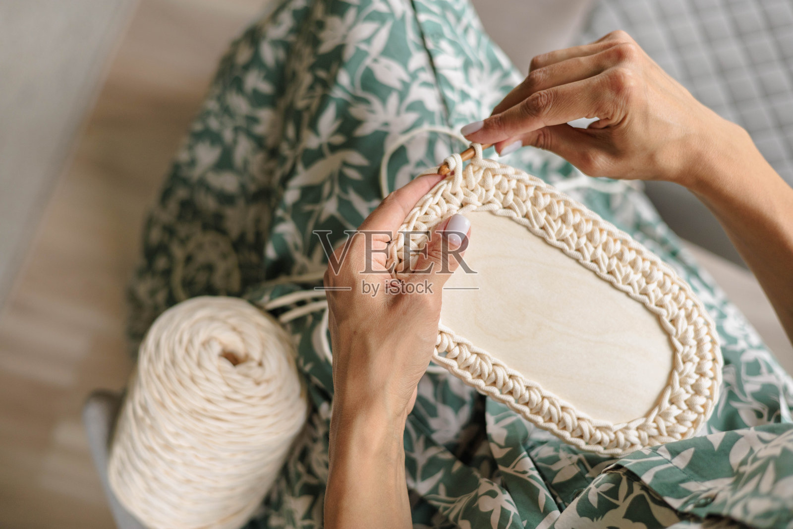 女性的手用白色和米色纱线钩织储物篮。女性的爱好的概念照片摄影图片