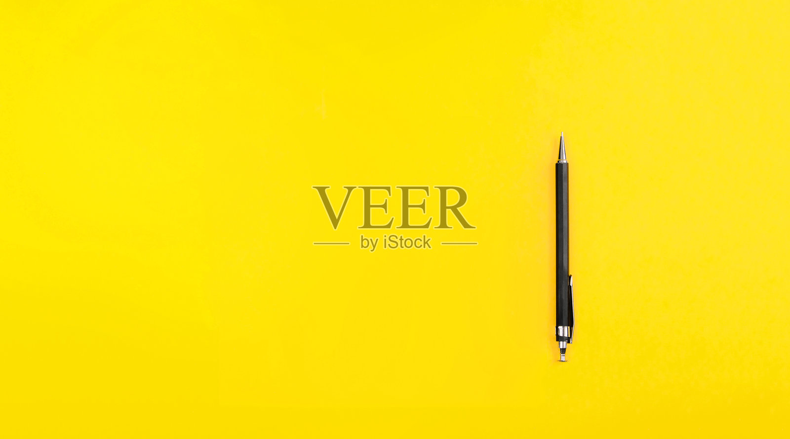 黑色金属笔尖的圆珠笔,背景为黄色,留有文本空白。学校教育。作家工具。带有自动铅笔的横幅。文具店广告。简单的名片。照片摄影图片