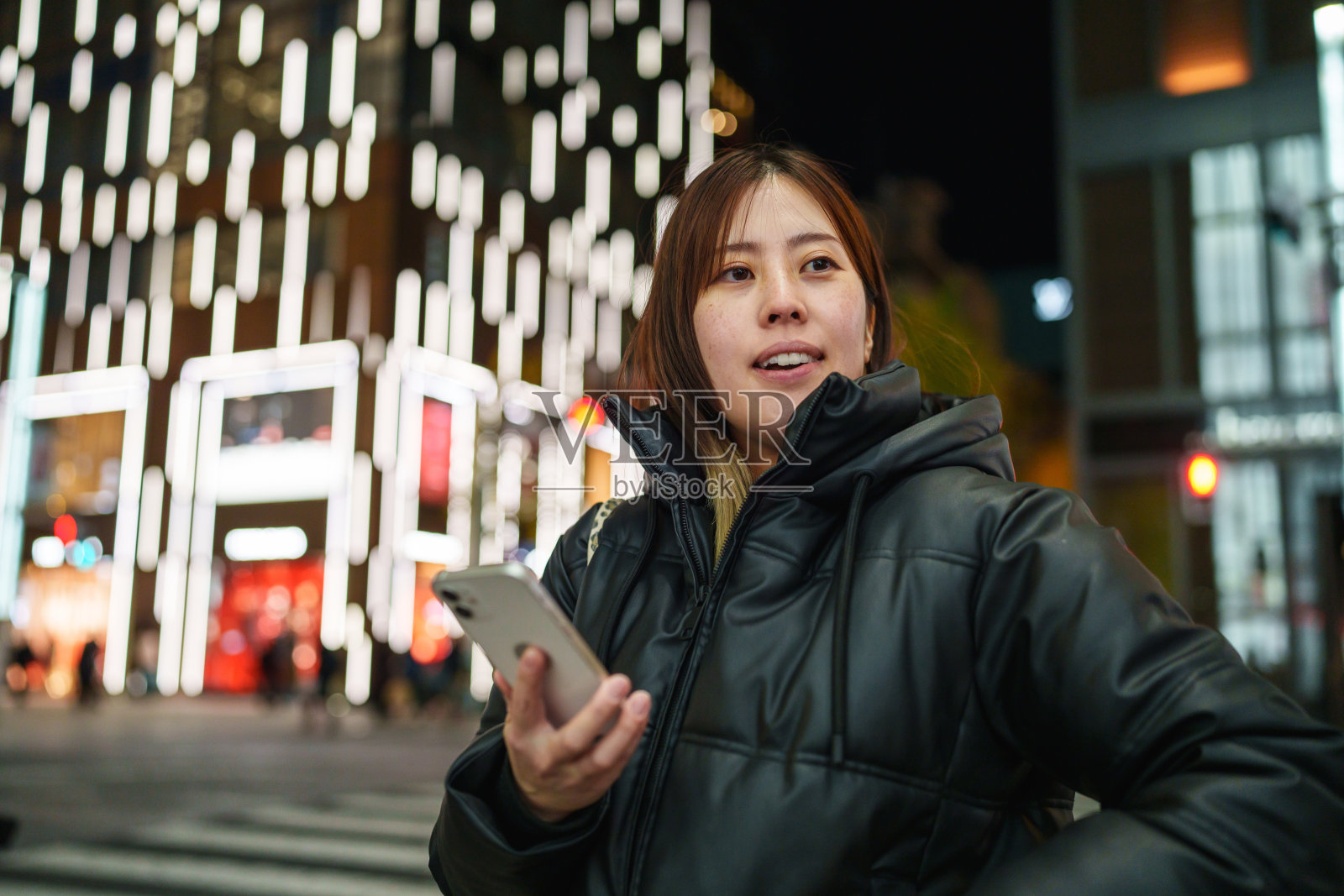 日本女性在夜晚的街道上使用手机。照片摄影图片