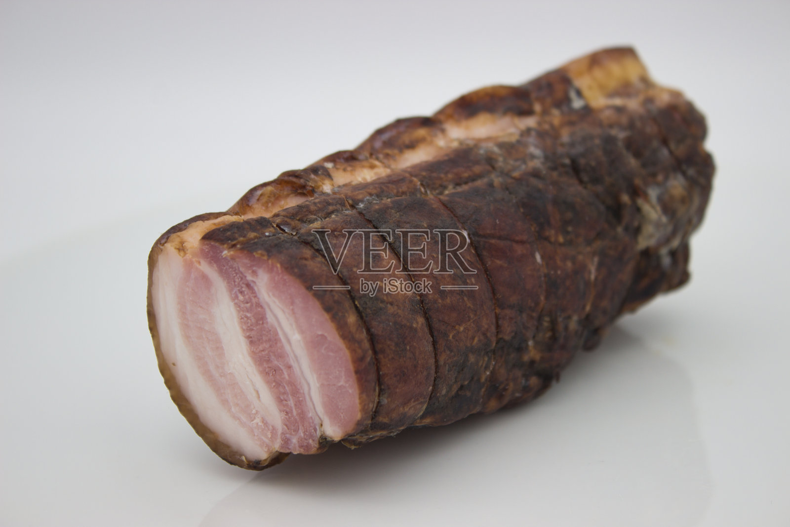 乡村风味的熏猪里脊肉,切成嫩滑多汁的片。照片摄影图片