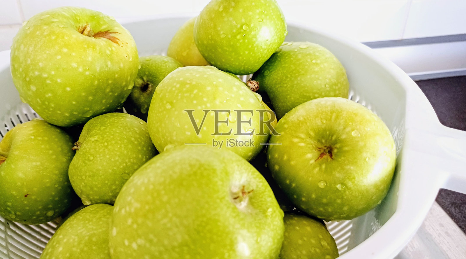 用筛子洗净的绿色苹果。照片摄影图片