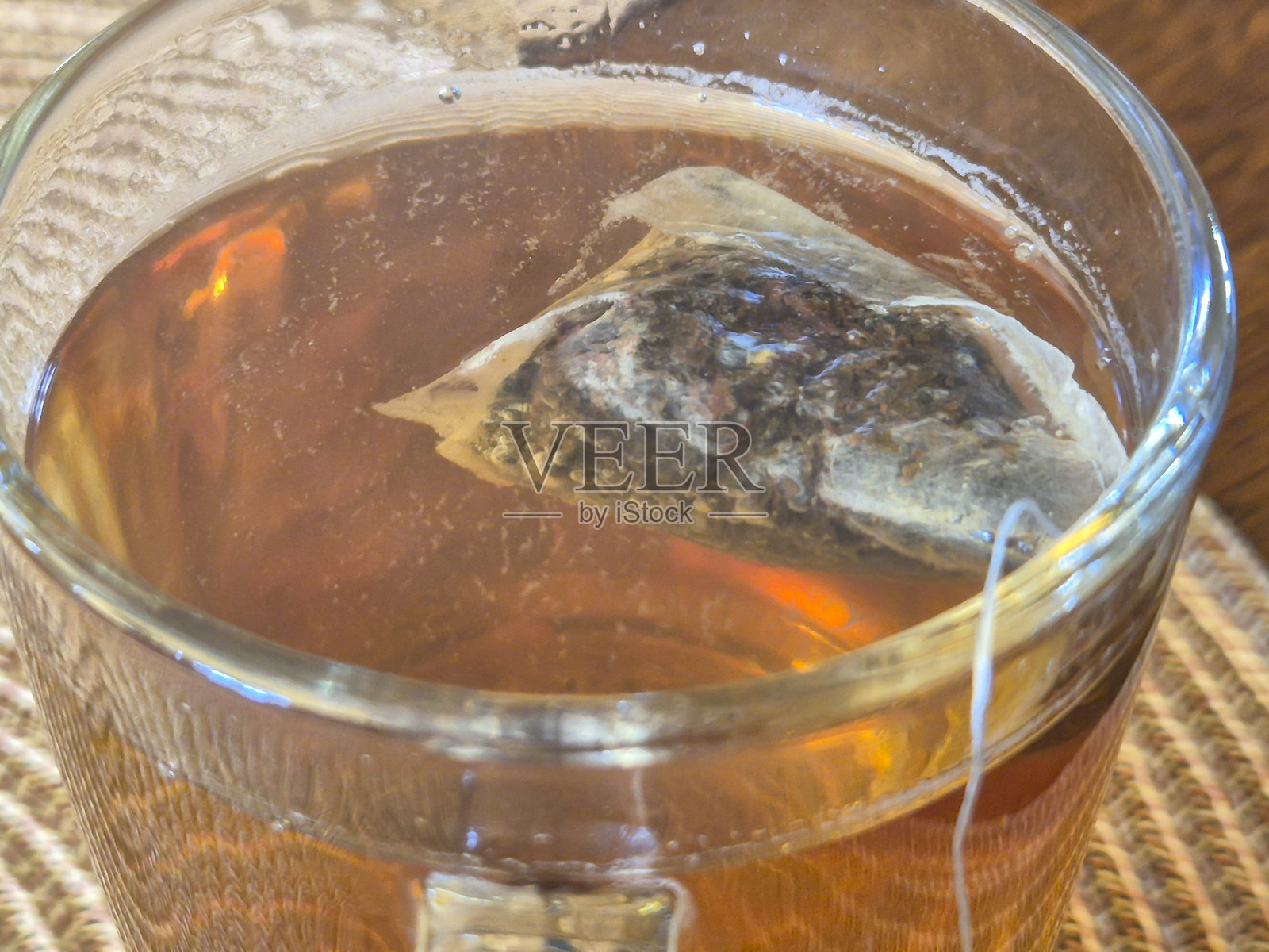 茶包浸泡在热茶中的特写,展现出丰富的色彩和质感。非常适合饮品和放松主题。照片摄影图片