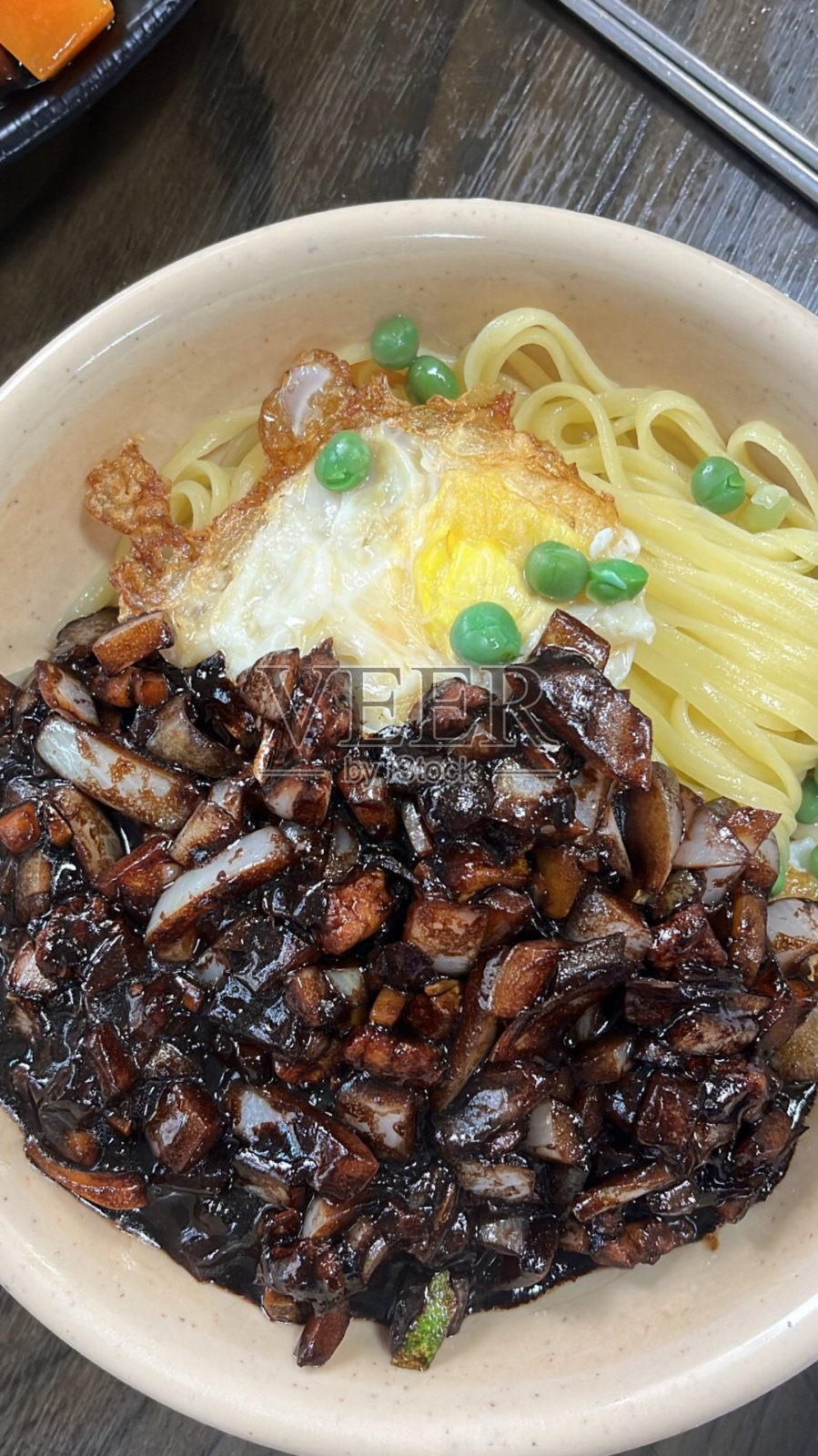 炸酱面是一道受欢迎的韩国菜,特色是厚实的小麦面条,上面浇有由春酱、 diced pork 和蔬菜制成的浓郁咸香黑豆酱。丰盛美味,是一顿令人舒适和满足的餐点。照片摄影图片