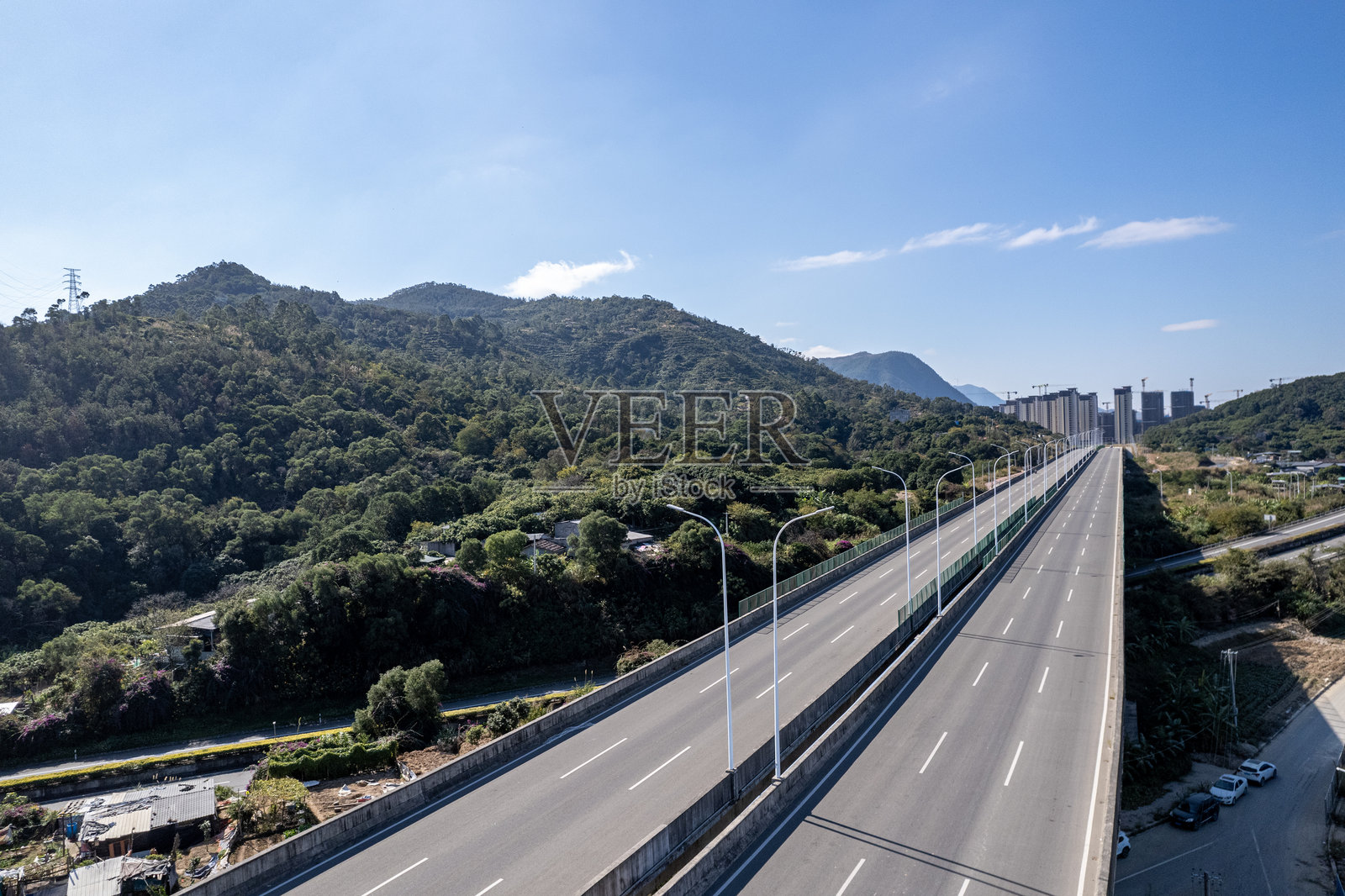 从空中俯瞰穿过山坡和田野的高速公路照片摄影图片