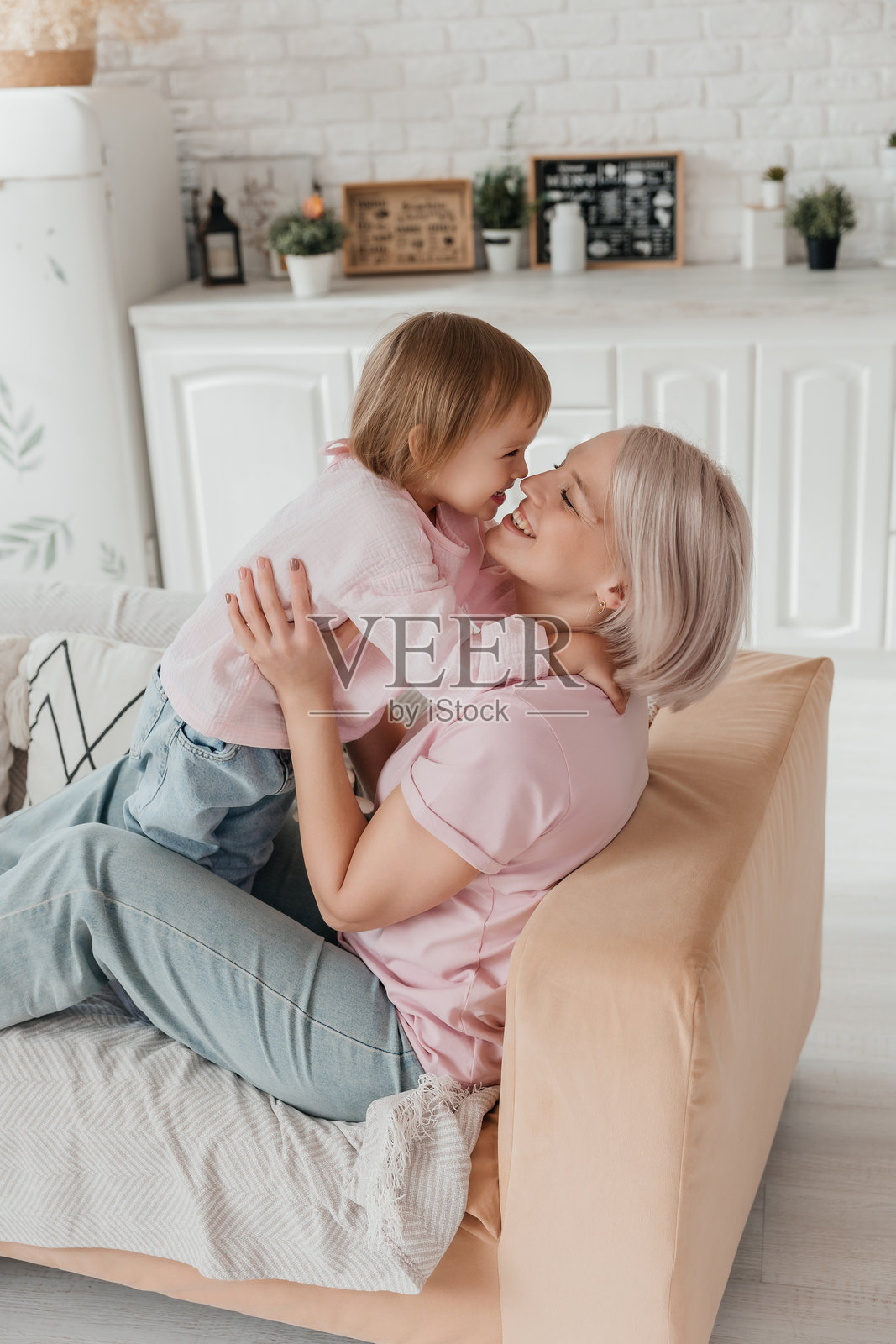 一个三岁的小女孩在明亮的客厅里和她的妈妈在沙发上玩耍。照片摄影图片