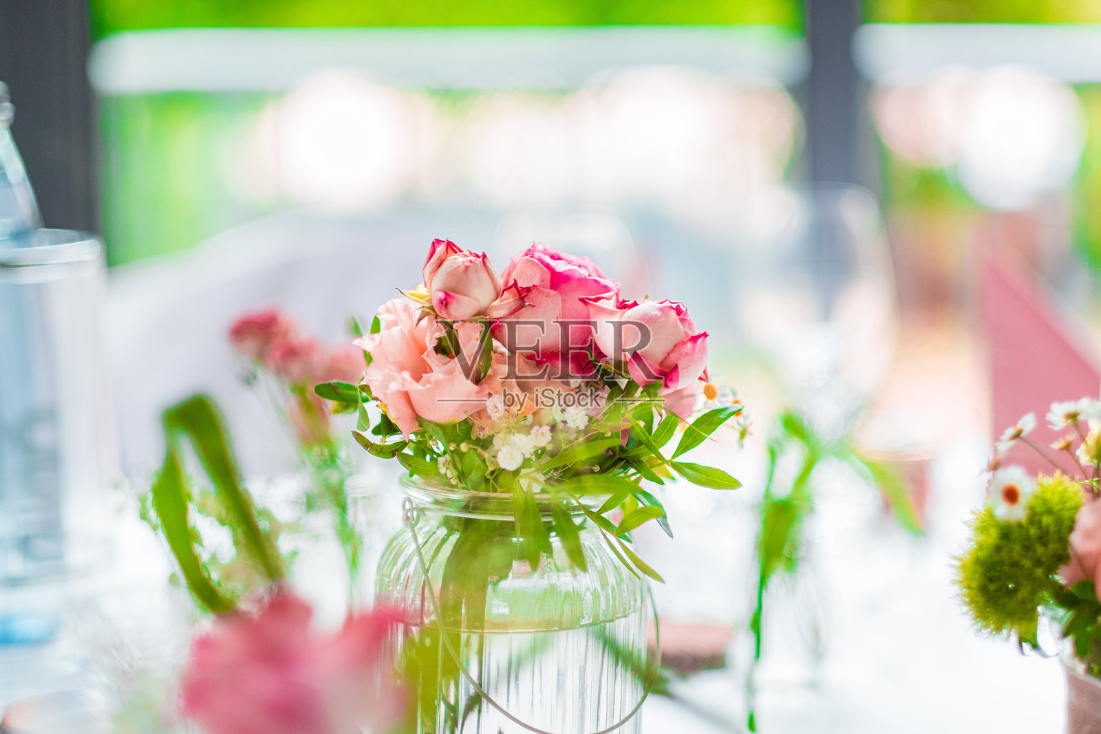 优雅的玻璃罐花瓶特写,里面装饰着美丽的粉色玫瑰和绿叶花卉组合照片摄影图片