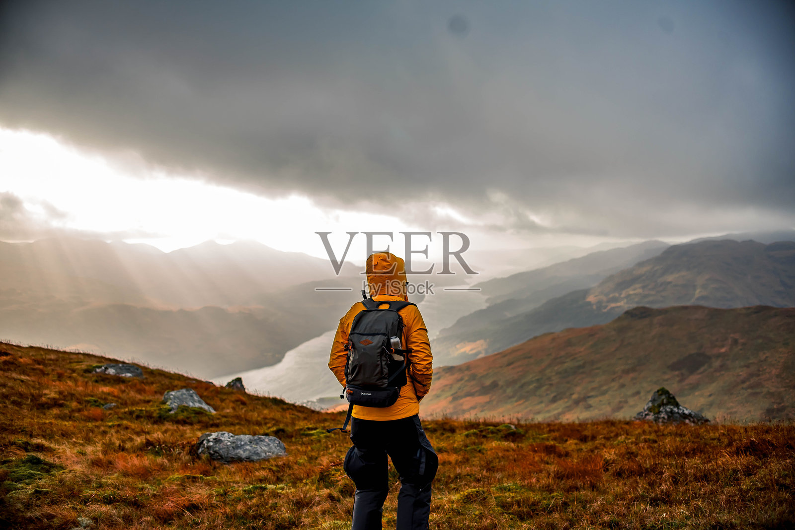 背对山脉的男子站在云雾缭绕的天空下照片摄影图片