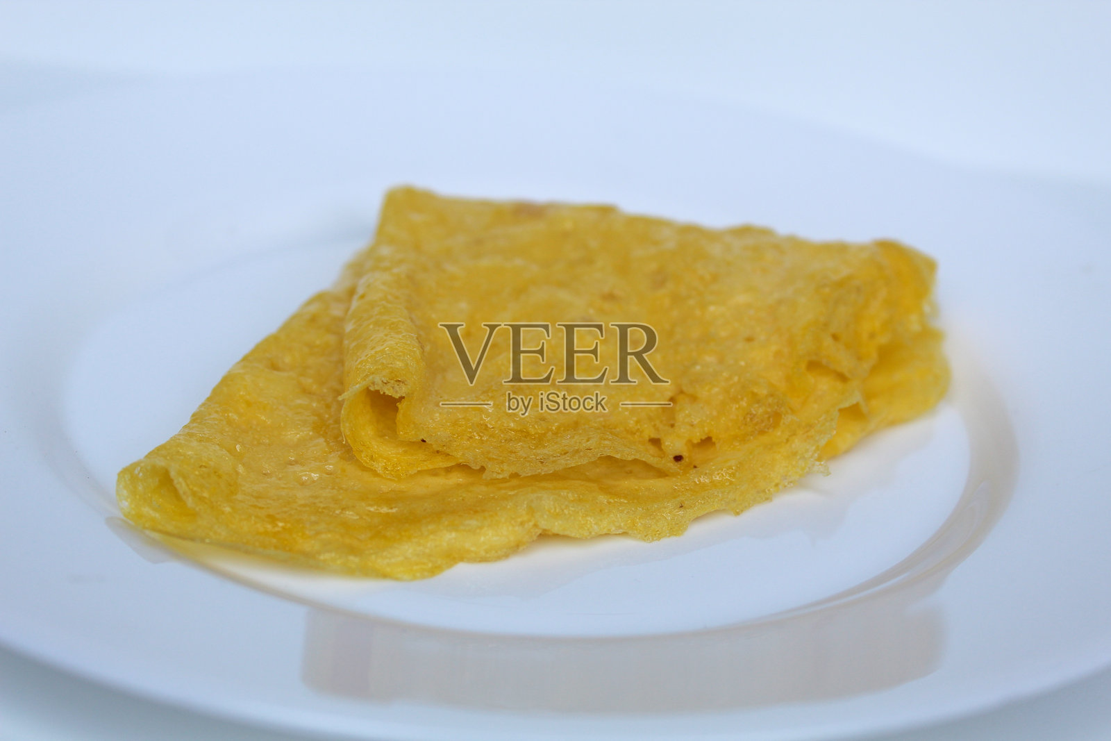 三角形折叠的煎蛋,放在白色盘子上,背景为白色照片摄影图片