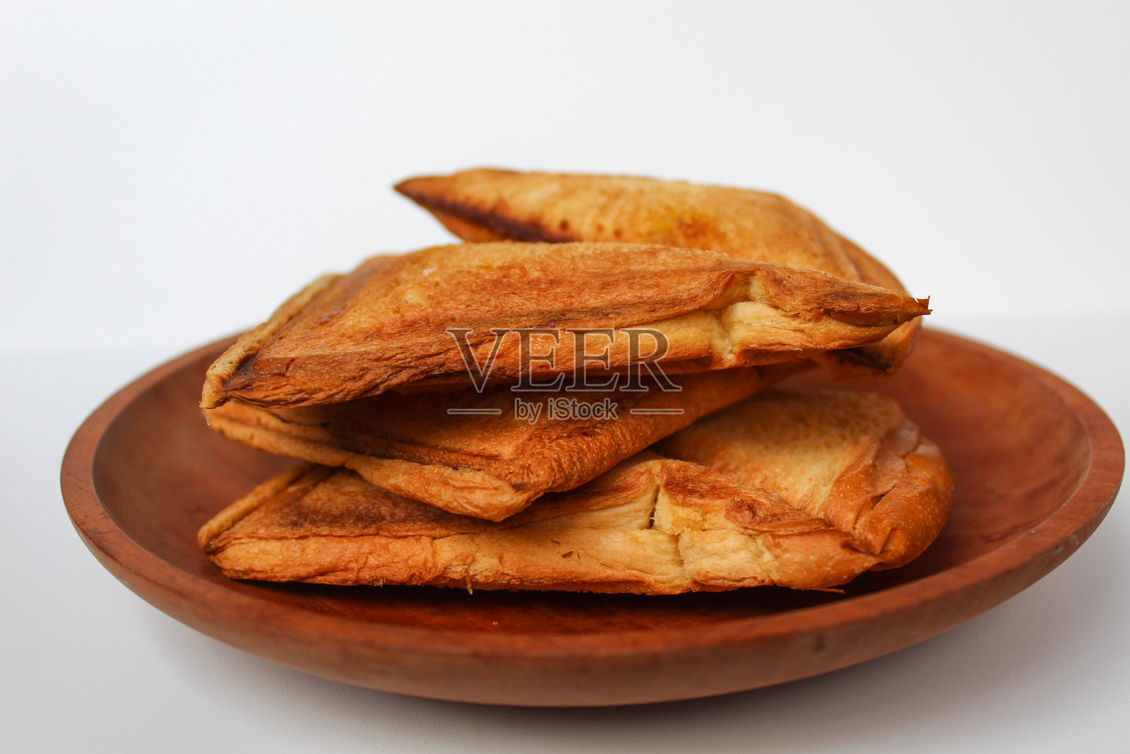 一些烤面包或烤面包片,放在木盘上,背景为白色照片摄影图片