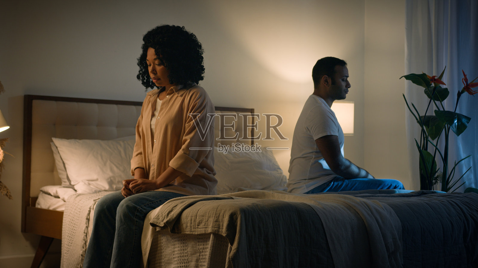 伤心的非裔美国女性妻子因与丈夫的勃起功能障碍问题而感到不快,女性安慰者触碰她,夫妻俩在夜晚的床上。照片摄影图片