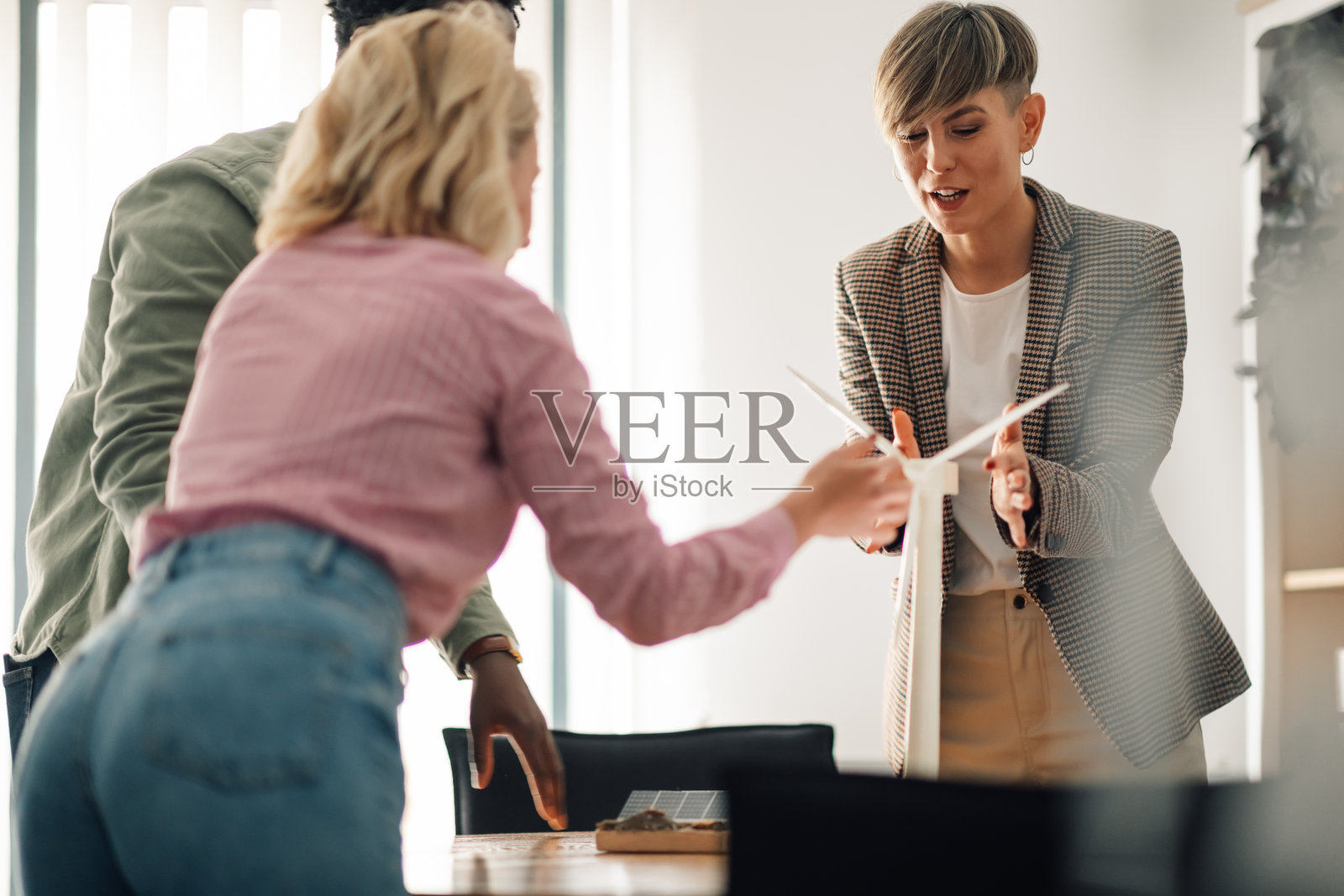 工程师们在可再生能源项目中合作,使用风力涡轮机模型照片摄影图片