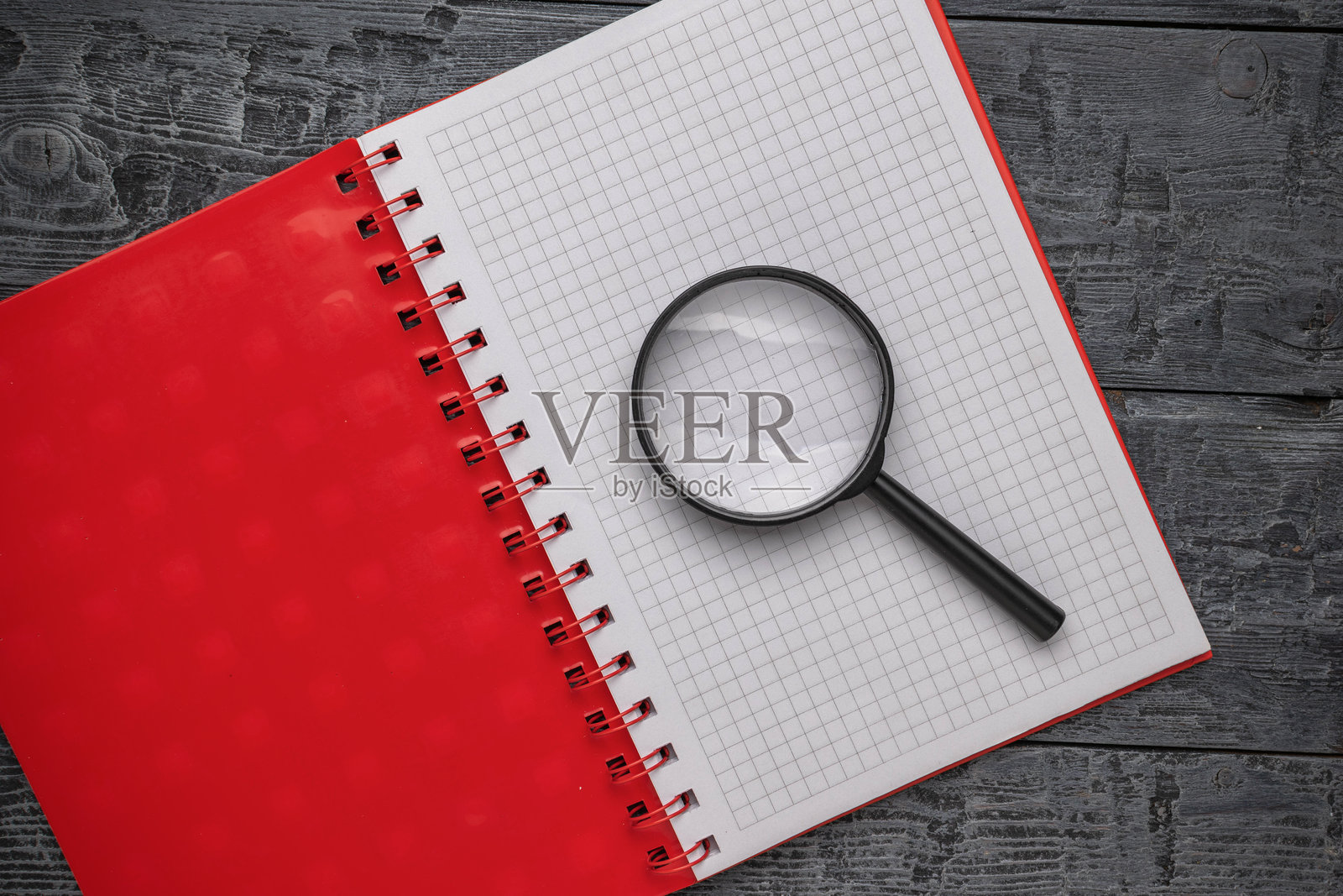 木桌上的红色封面笔记本上的放大镜照片摄影图片