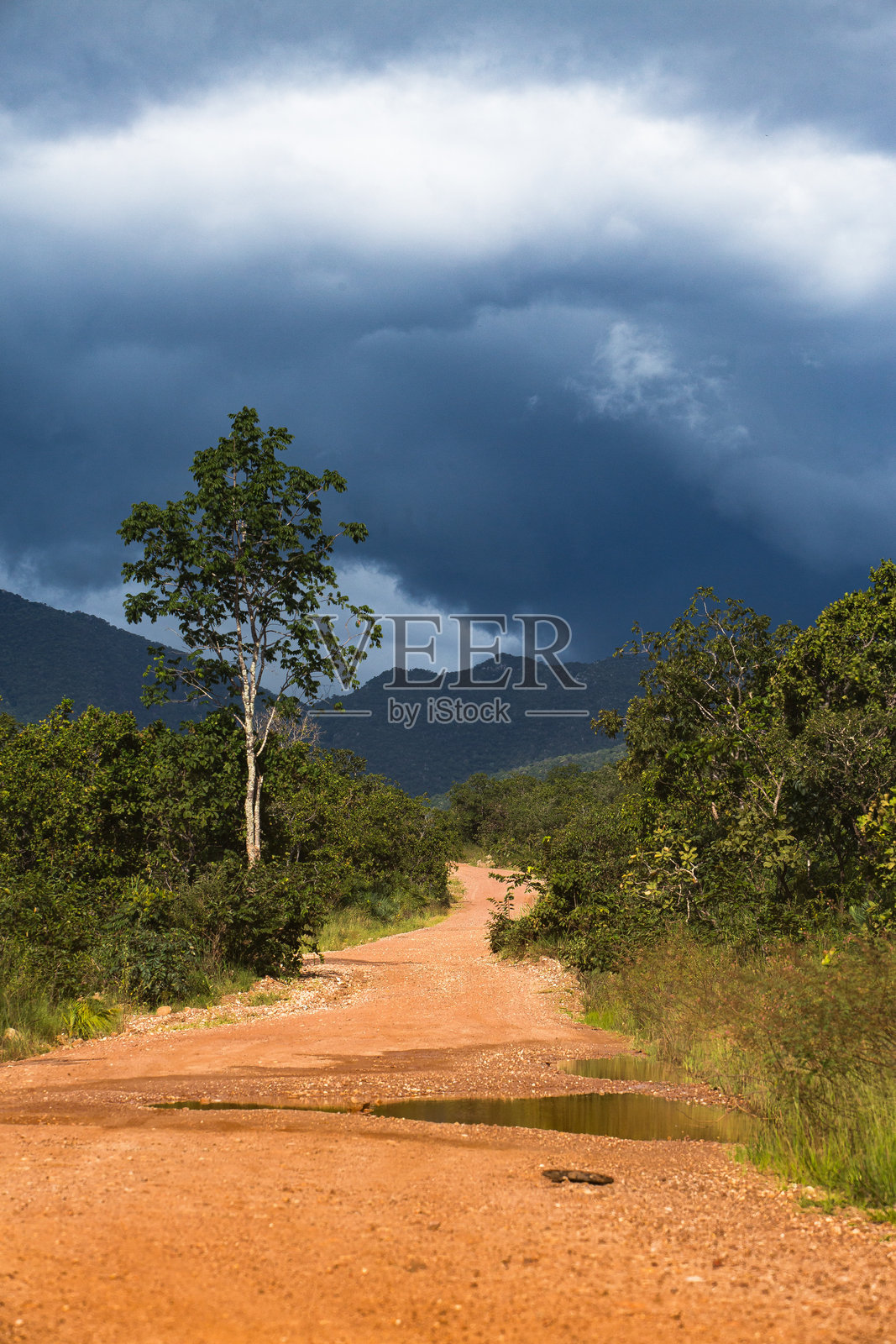 泥土路上有水坑,天空戏剧性地变化照片摄影图片