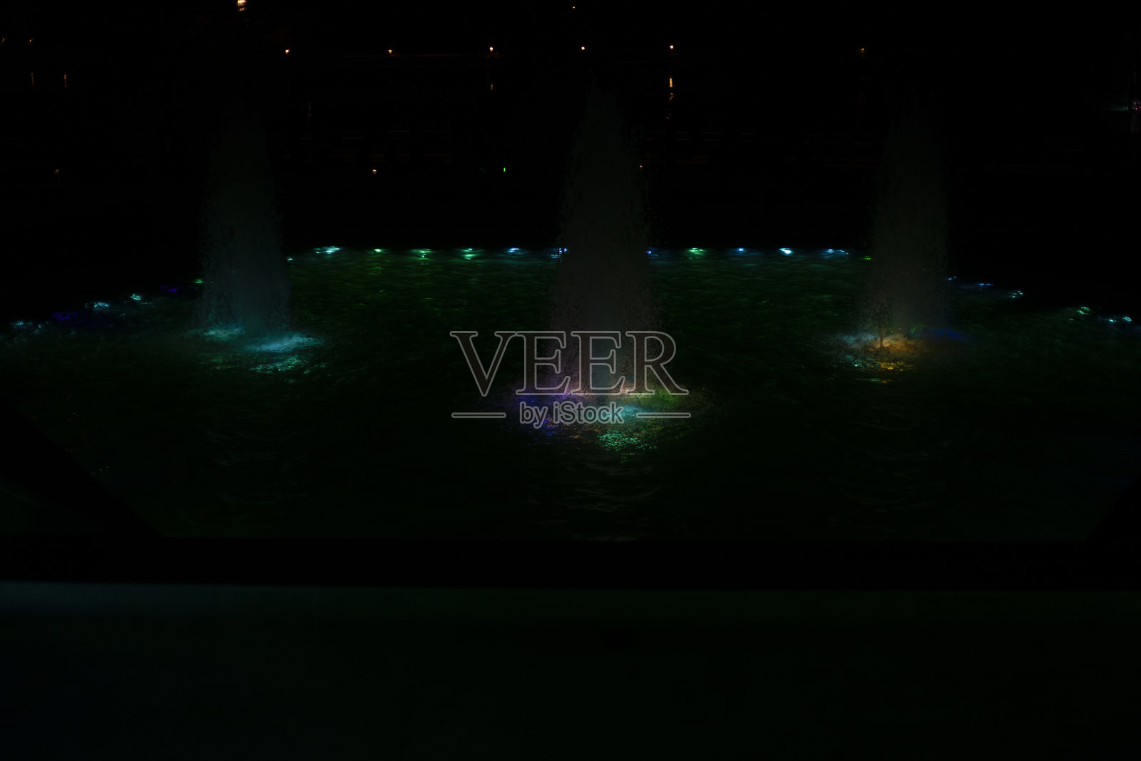 照明喷泉。LED灯照耀着水面。喷泉在多彩灯光下。照片摄影图片