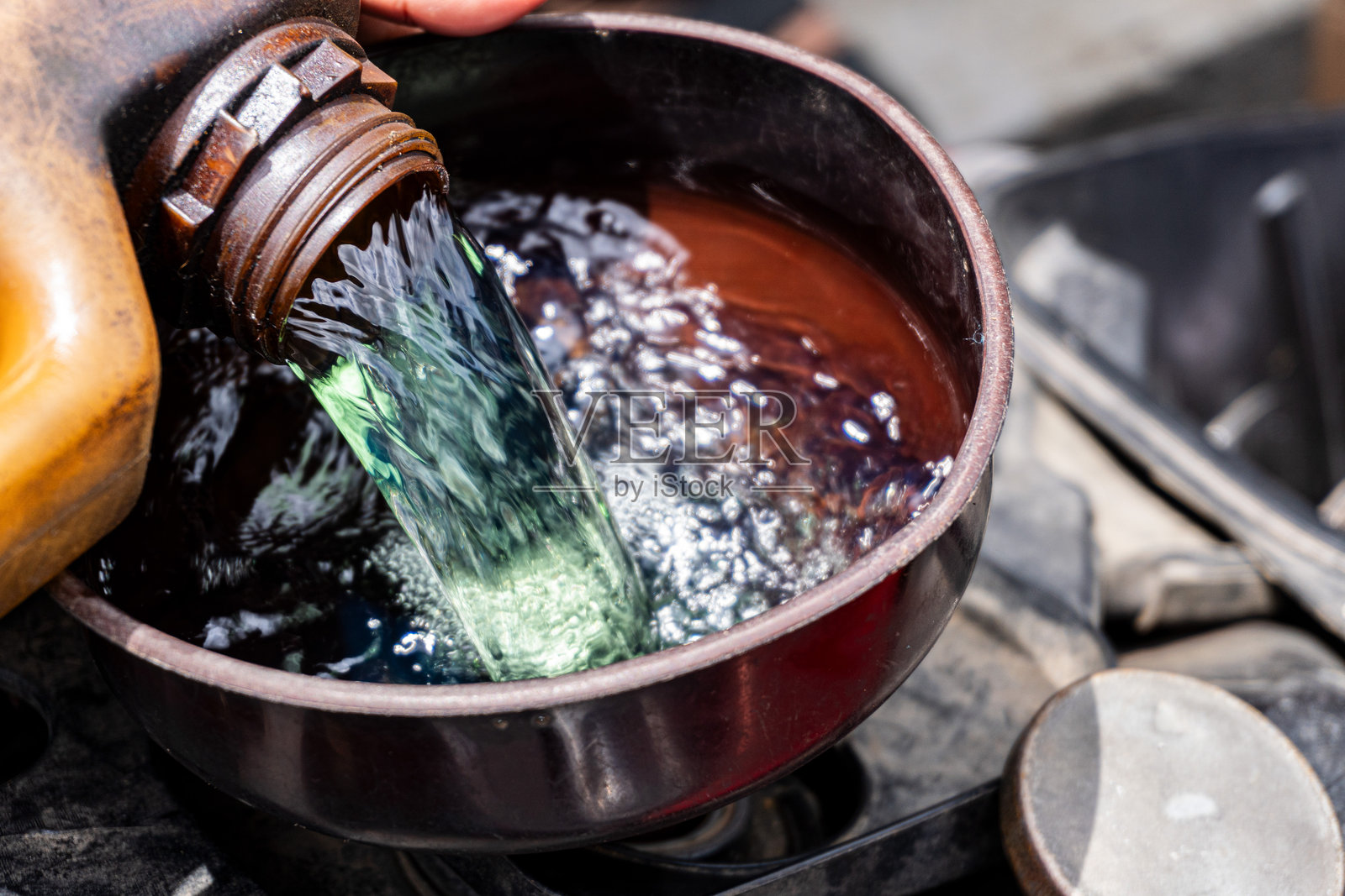 有人将燃料或汽油倒入摩托车油箱。街头燃料销售员照片摄影图片