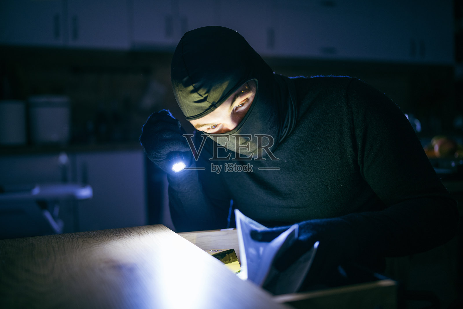 戴面具的小偷闯入房屋。照片摄影图片