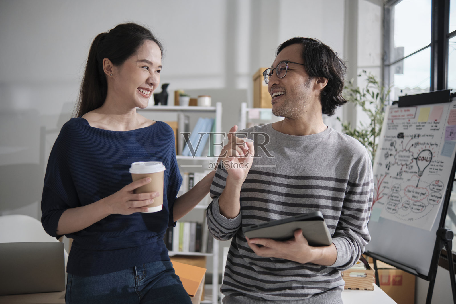 两位年轻的亚洲创业伙伴在一个休闲的小型办公室里工作。照片摄影图片