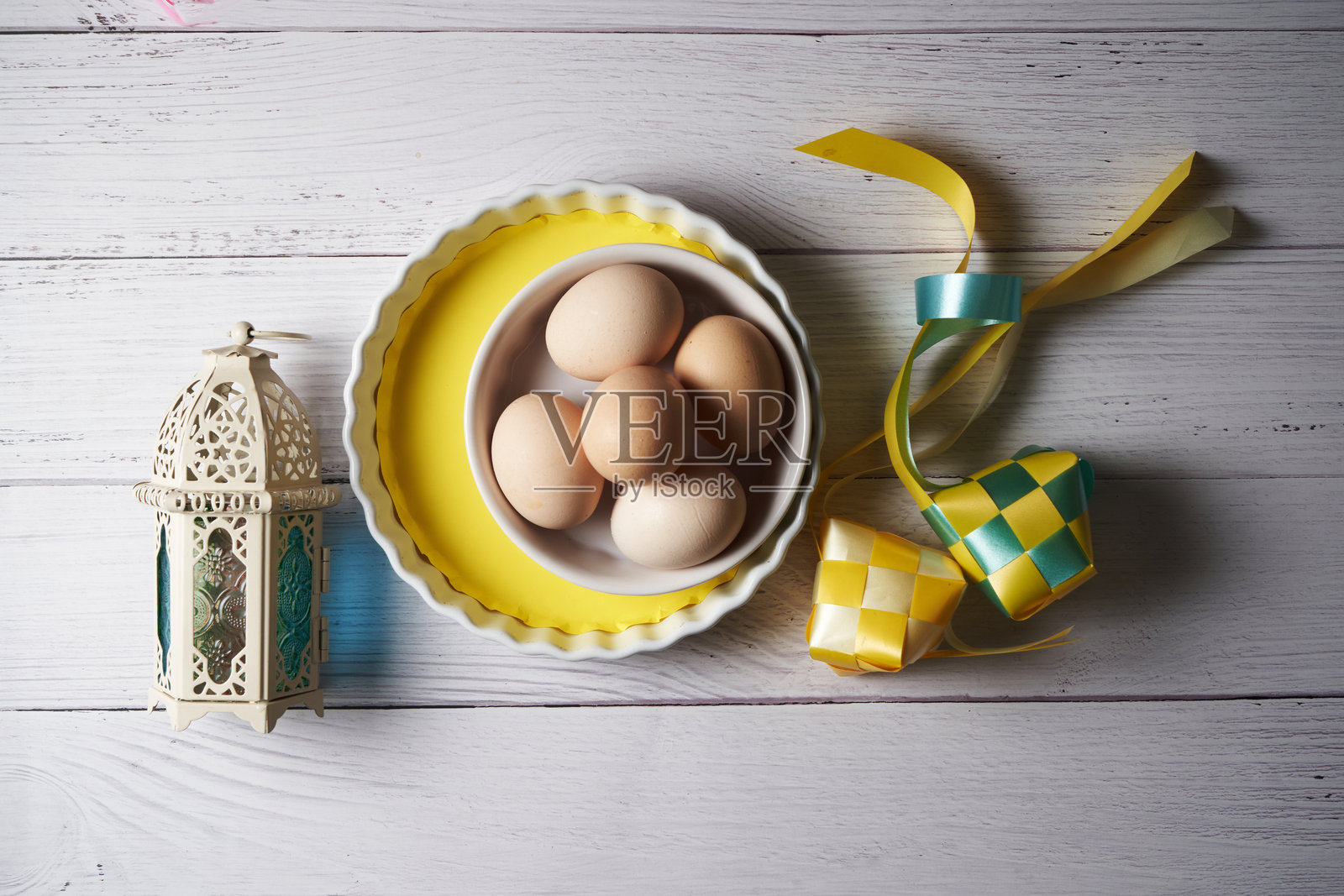 两个饼干模具形成新月形状,上面放着鸡蛋和阿拉伯灯,背景是木质的。照片摄影图片