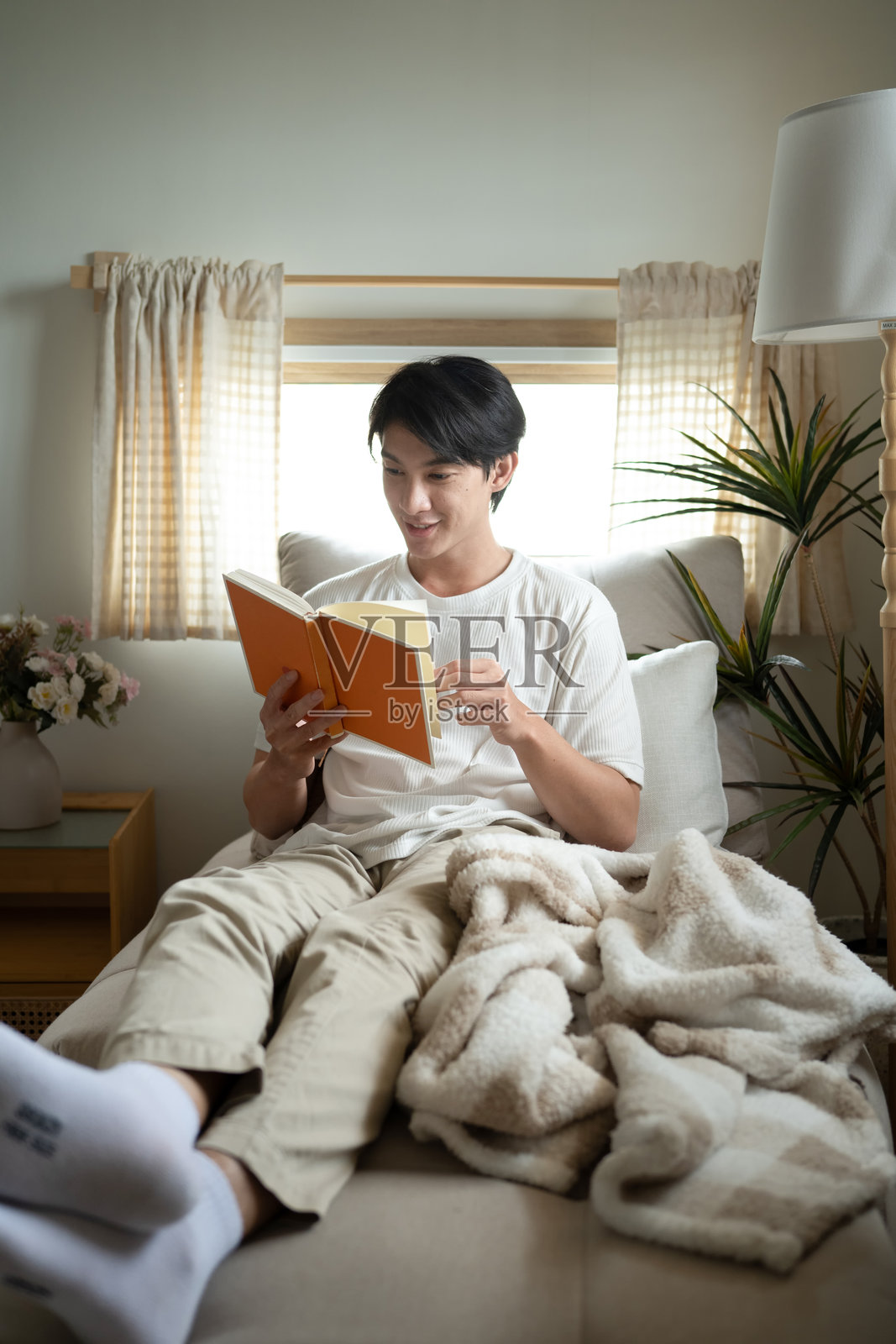 平静的千禧一代男性在家中沙发上放松阅读书籍照片摄影图片