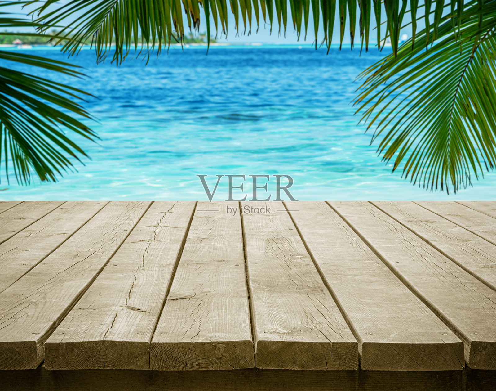 空荡荡的木桌面,背景是美丽的热带碧蓝海洋和棕榈叶,留有空白空间的场景照片摄影图片