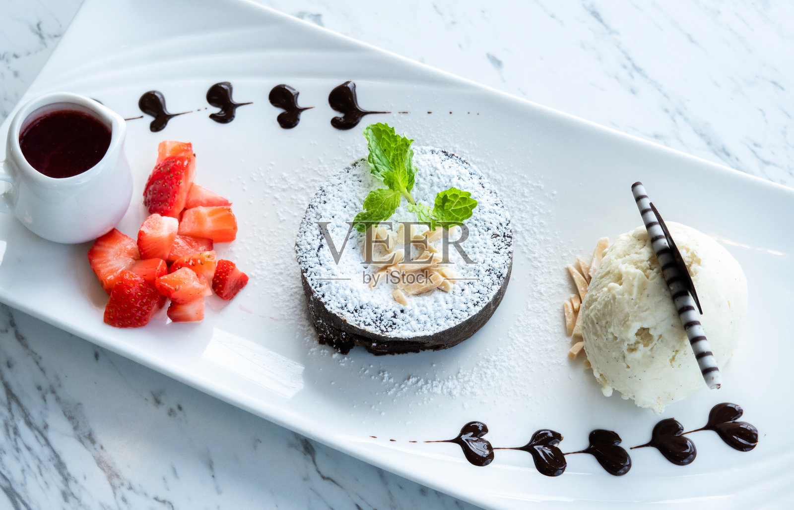 巧克力软糖熔岩蛋糕,草莓和香草冰淇淋装在盘子里照片摄影图片