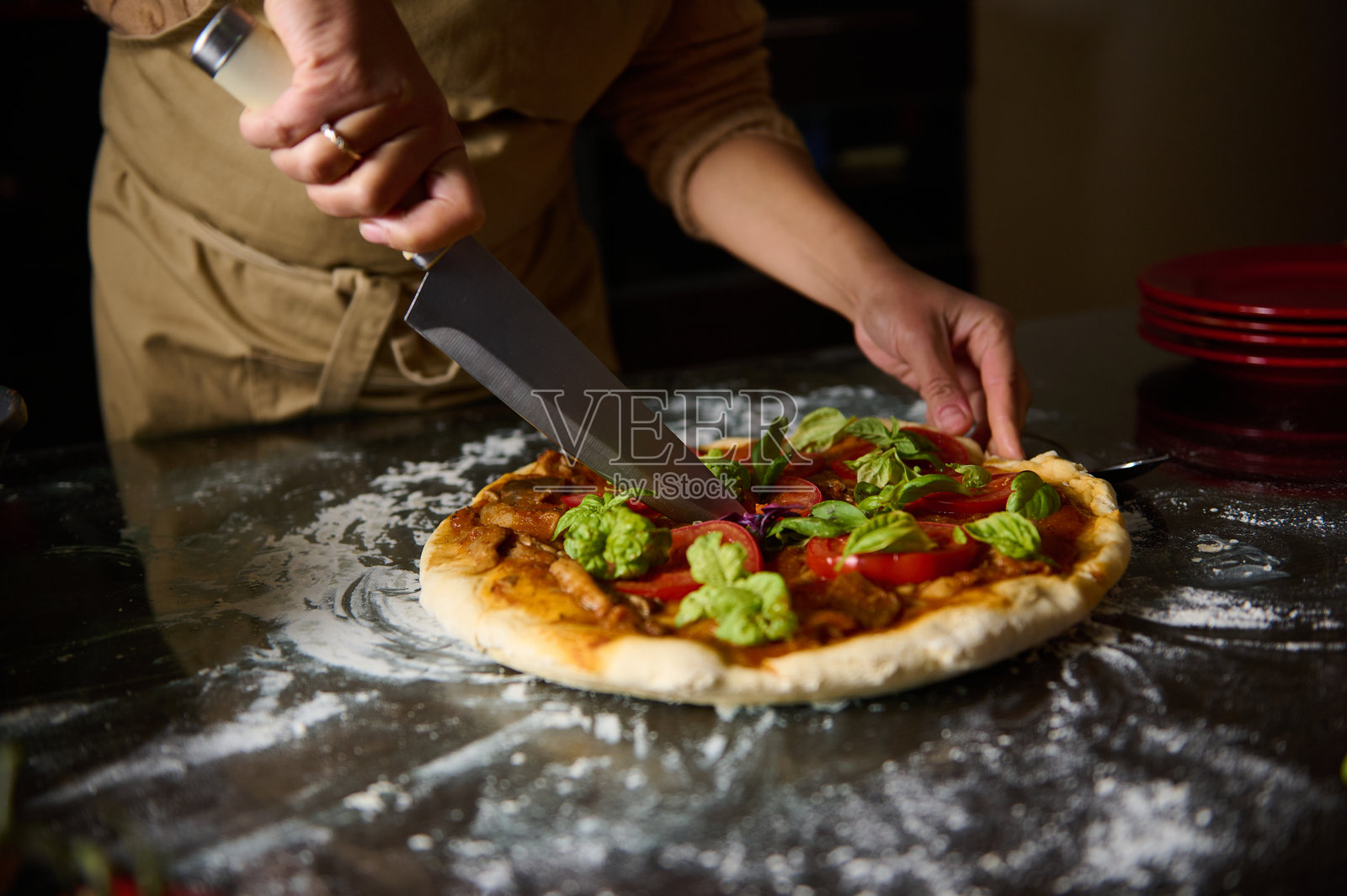一个人在撒了面粉的台面上用大刀切新鲜制作的比萨饼照片摄影图片