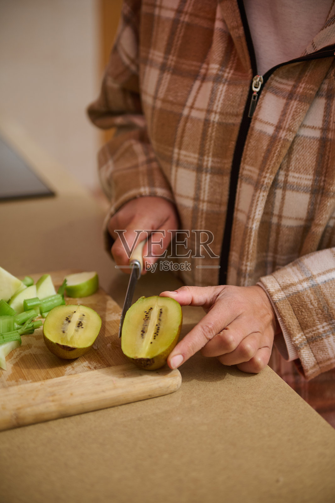 女人在厨房台面上切奇异果照片摄影图片