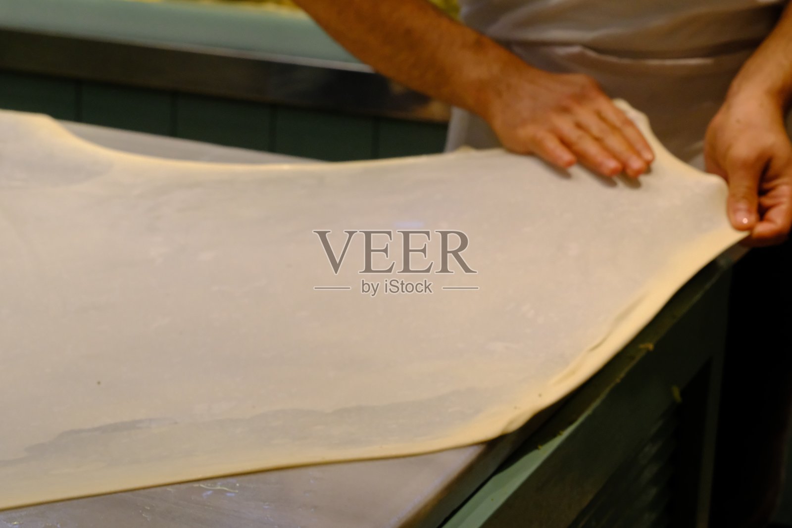 一位糕点厨师正在整理他擀好的薄薄的巴克拉瓦面团照片摄影图片