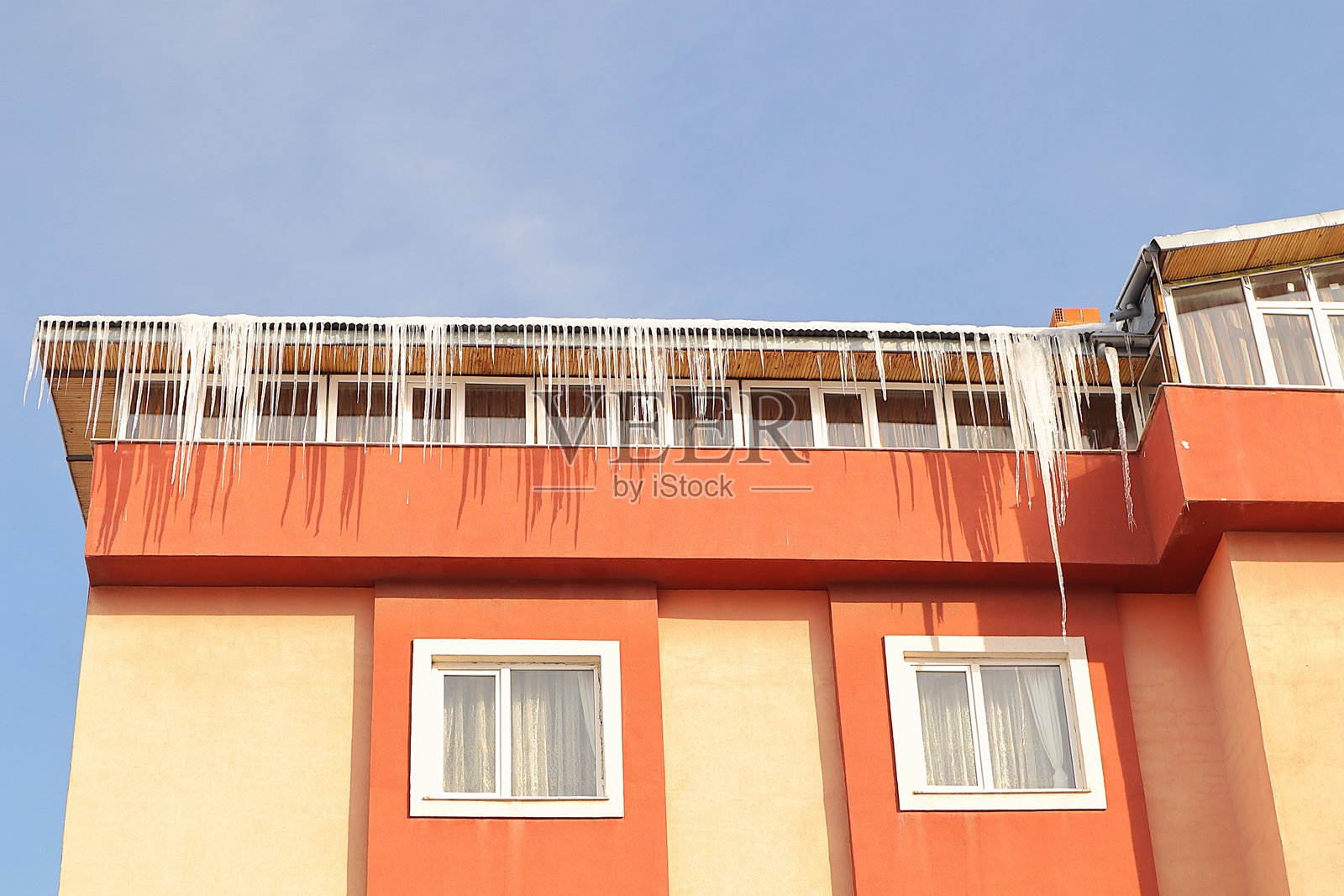 巨大的冰柱悬挂在土耳其埃尔祖鲁姆一栋建筑的屋檐边缘,冬季气温可降至-50°C。这是极寒天气下令人惊叹的自然现象。照片摄影图片