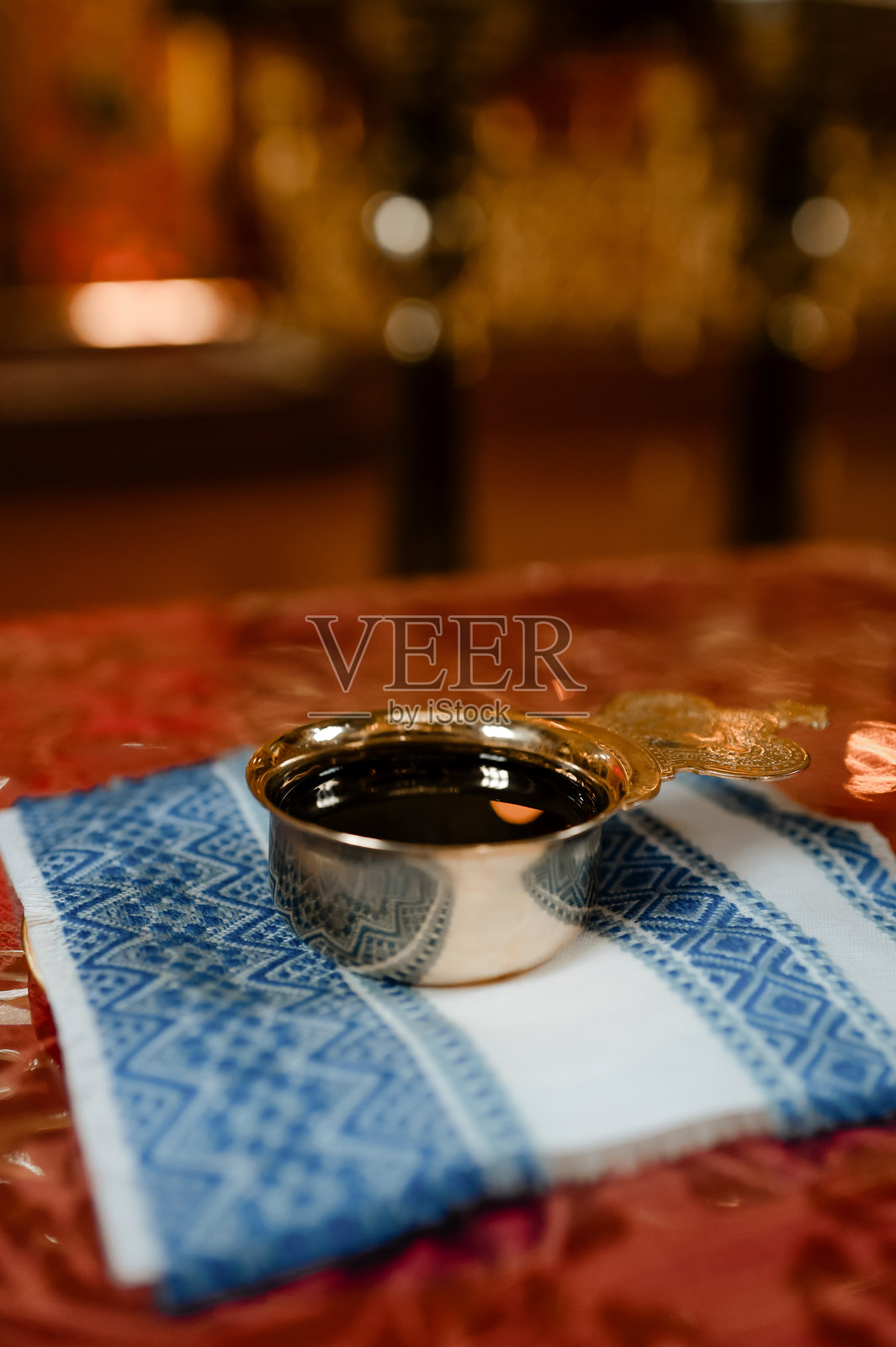 在东正教教堂中,婚礼用的金杯与葡萄酒,放在刺绣蓝色餐巾上。照片摄影图片