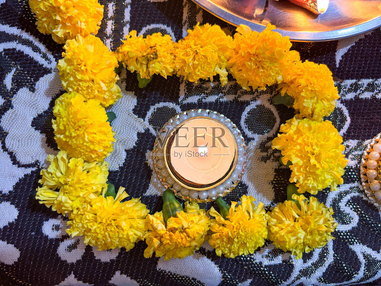 A candle is lit in a yellow flower arrangement照片摄影图片