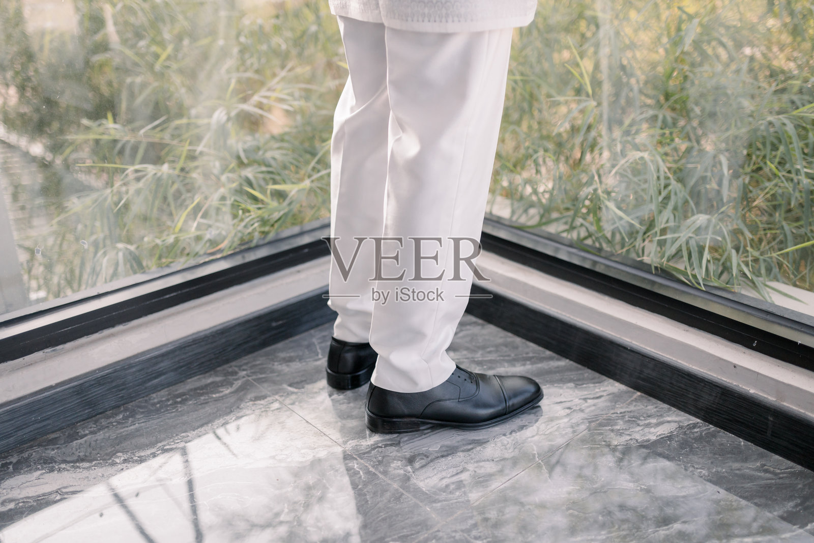 穿着白色传统马来服装的男性摆婚礼姿势,搭配沙龙和便鞋。照片摄影图片