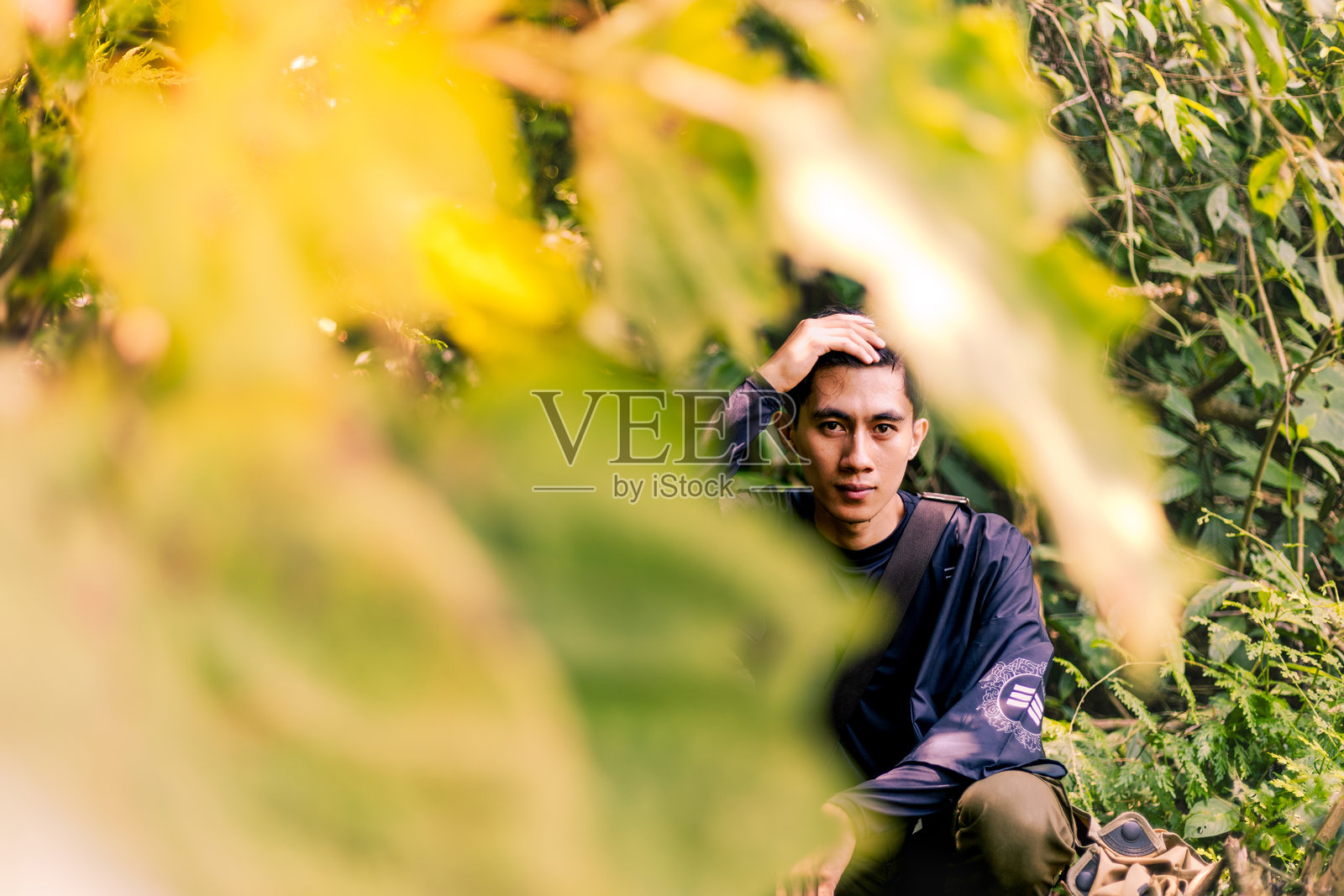 沉思的男人坐着,直视镜头。男人拥抱自然:享受大自然的美好。照片摄影图片