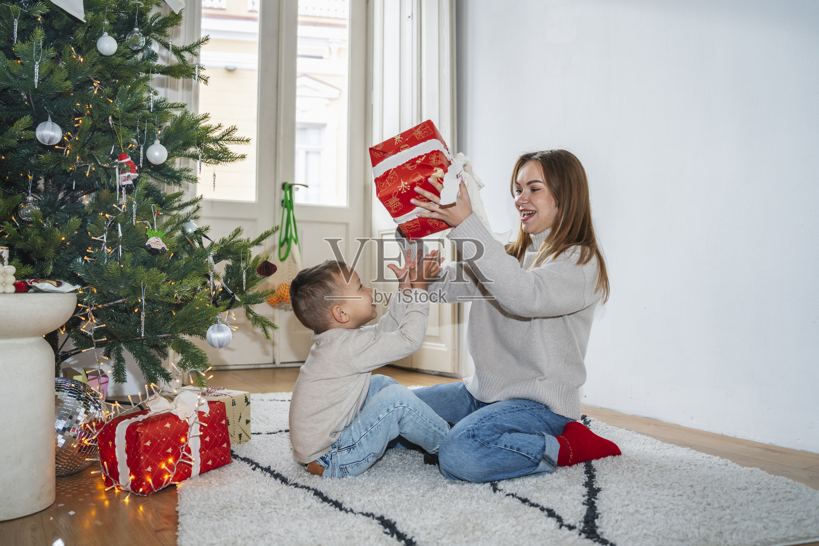 母亲和儿子在装饰好的圣诞树旁庆祝圣诞节照片摄影图片
