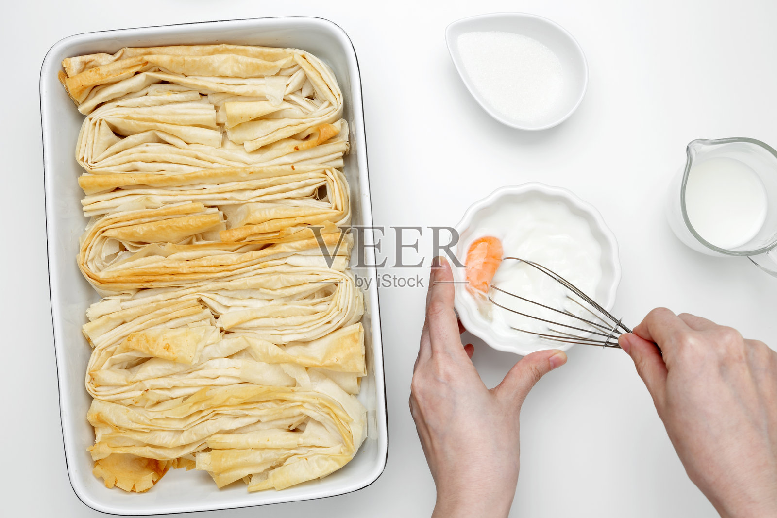 烤制的酥皮面团用于皱纹蛋糕,混合鸡蛋、牛奶和糖制作奶油。照片摄影图片