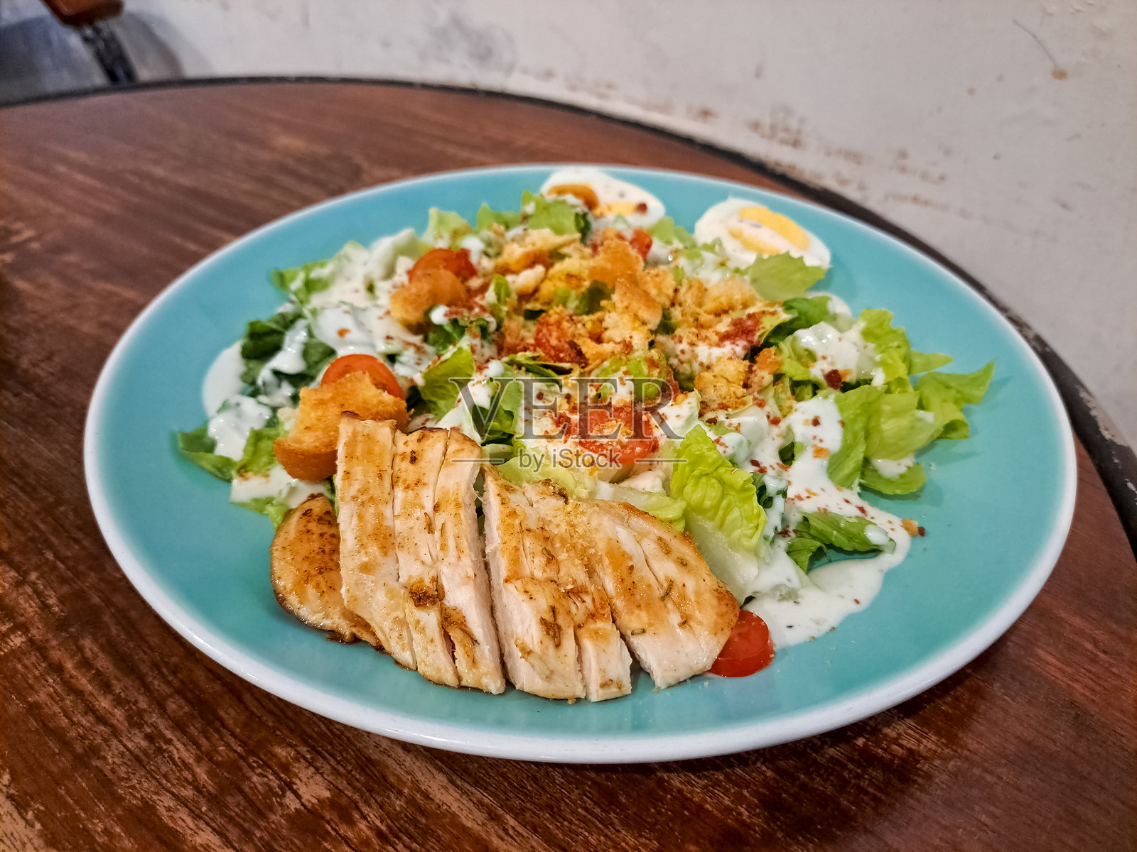 美味的凯撒鸡肉沙拉,配有罗马生菜、烤鸡胸肉、煮鸡蛋、大蒜面包、樱桃番茄和凯撒酱。菜单。照片摄影图片