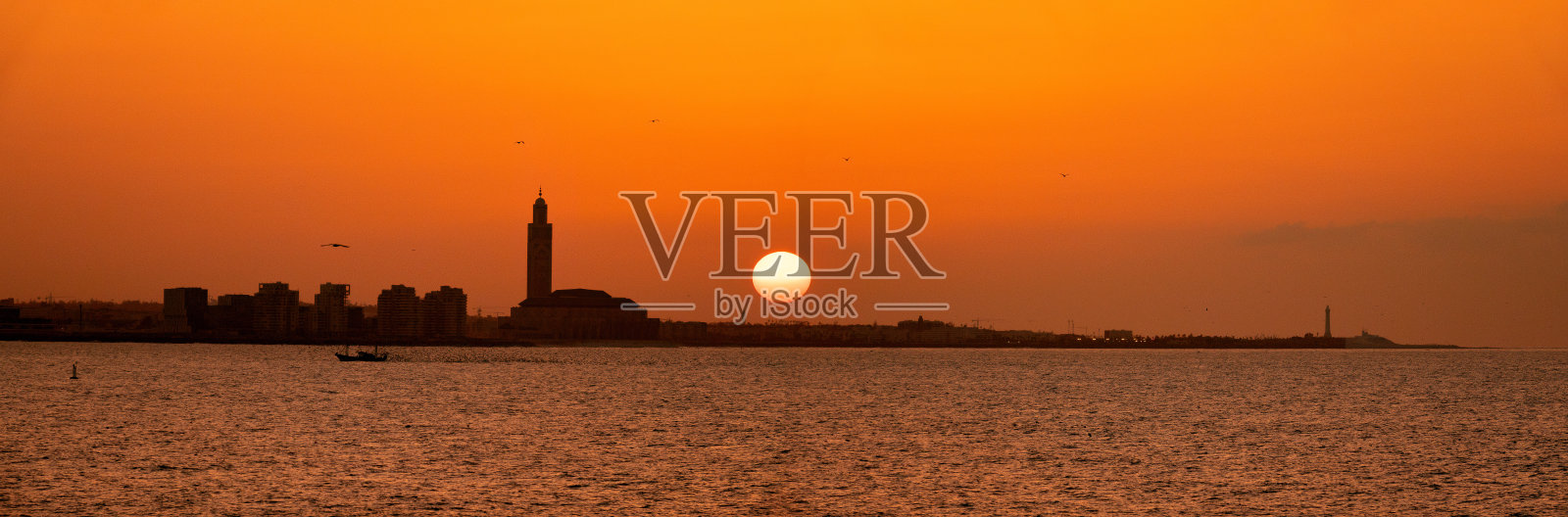 卡萨布兰卡海滨的全景,正值日落前。哈桑二世清真寺的尖塔(世界最高)在天际线中显得格外突出,摩洛哥卡萨布兰卡。照片摄影图片