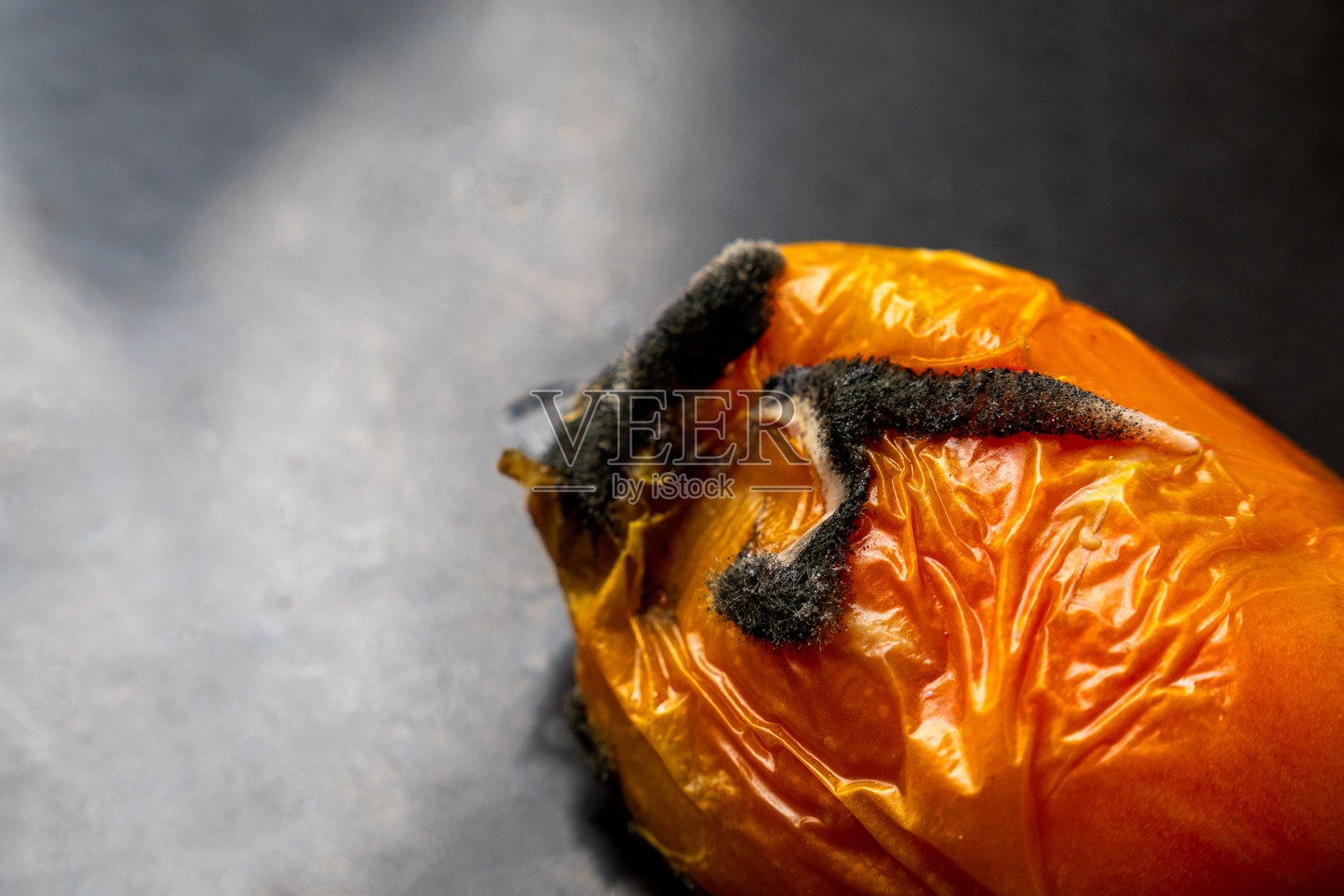 特写镜头展示一颗长霉的腐烂番茄,市场上的腐烂食物是健康隐患。照片摄影图片