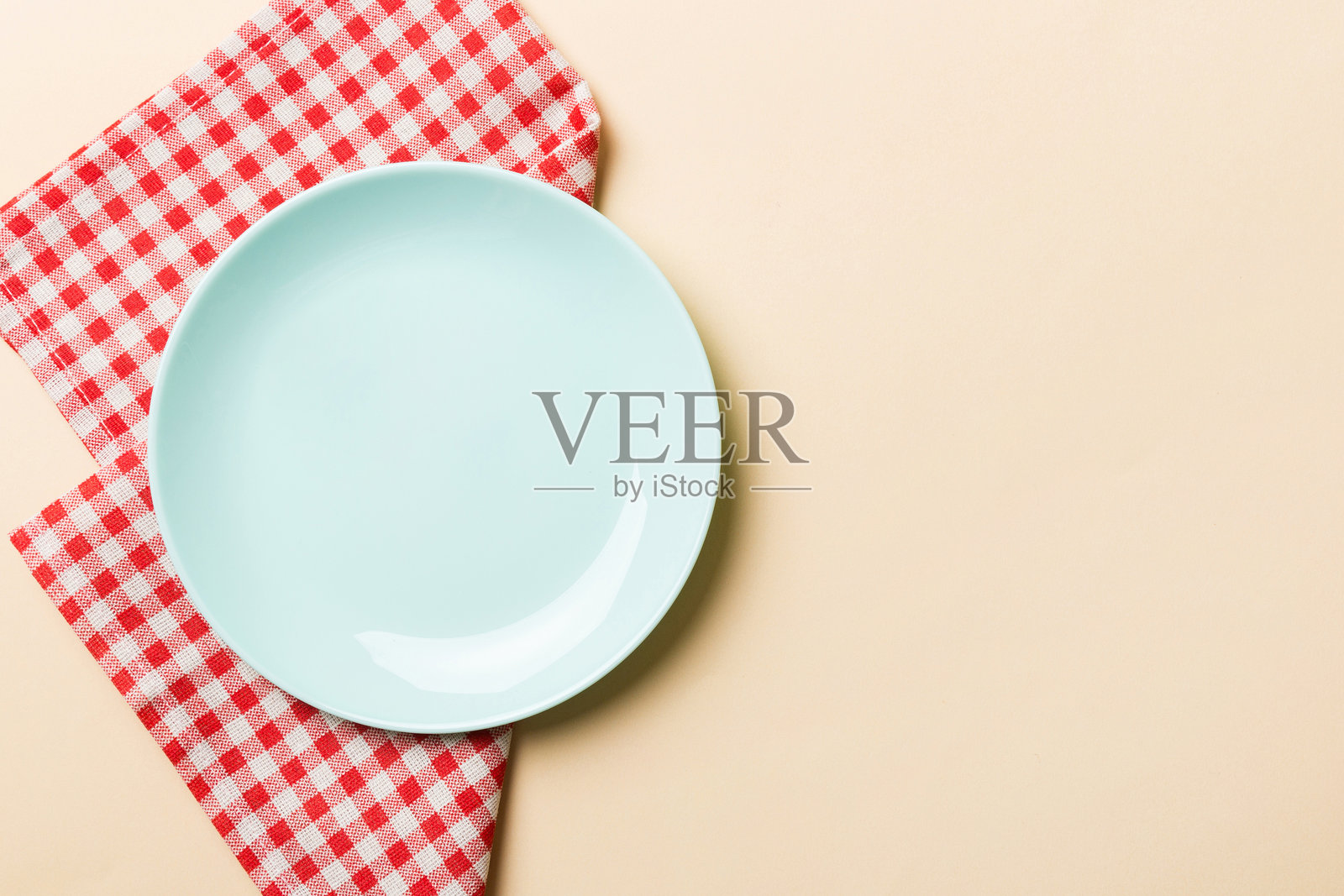 顶部视角,彩色背景下空的蓝色圆盘放在桌布上。空盘子放在餐巾上,留有空间供您设计。照片摄影图片