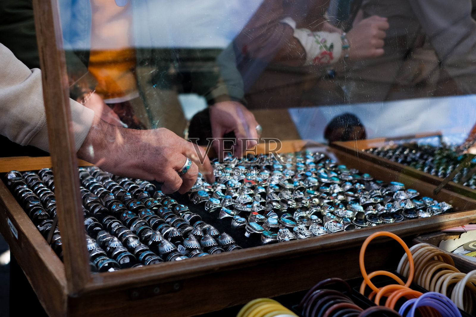 手放在展示柜中的戒指里照片摄影图片