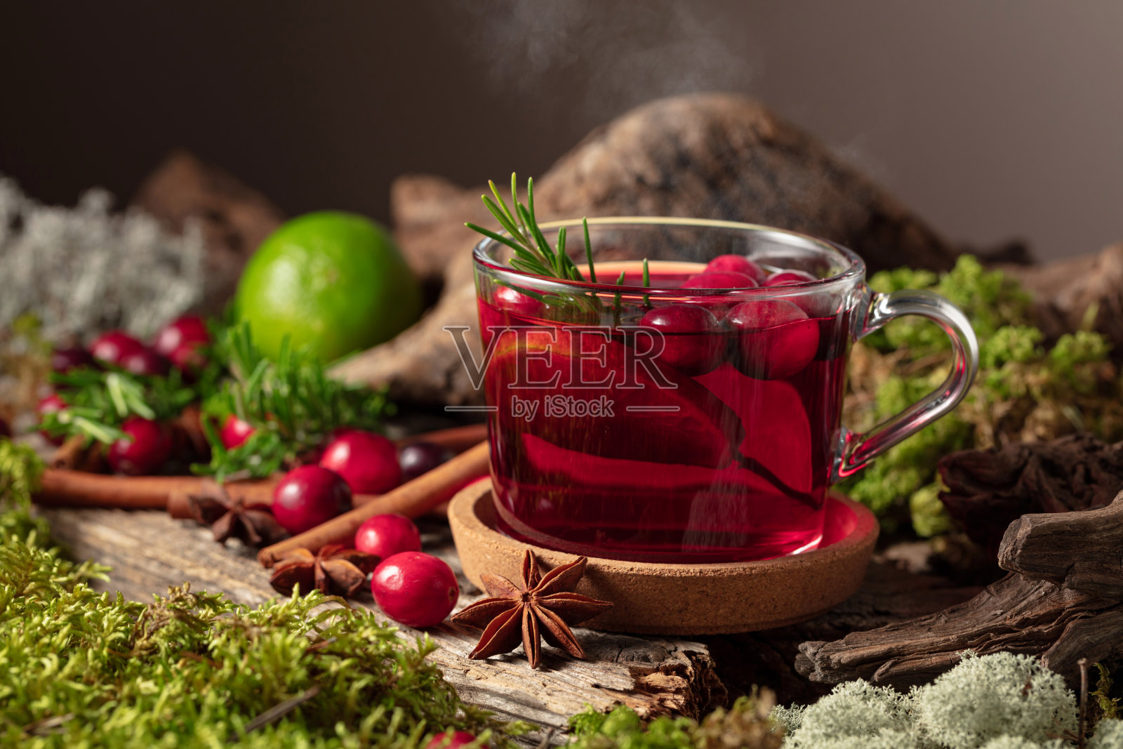 热冬饮,配有蔓越莓、青柠和迷迭香,摆放在古老的木板上。照片摄影图片
