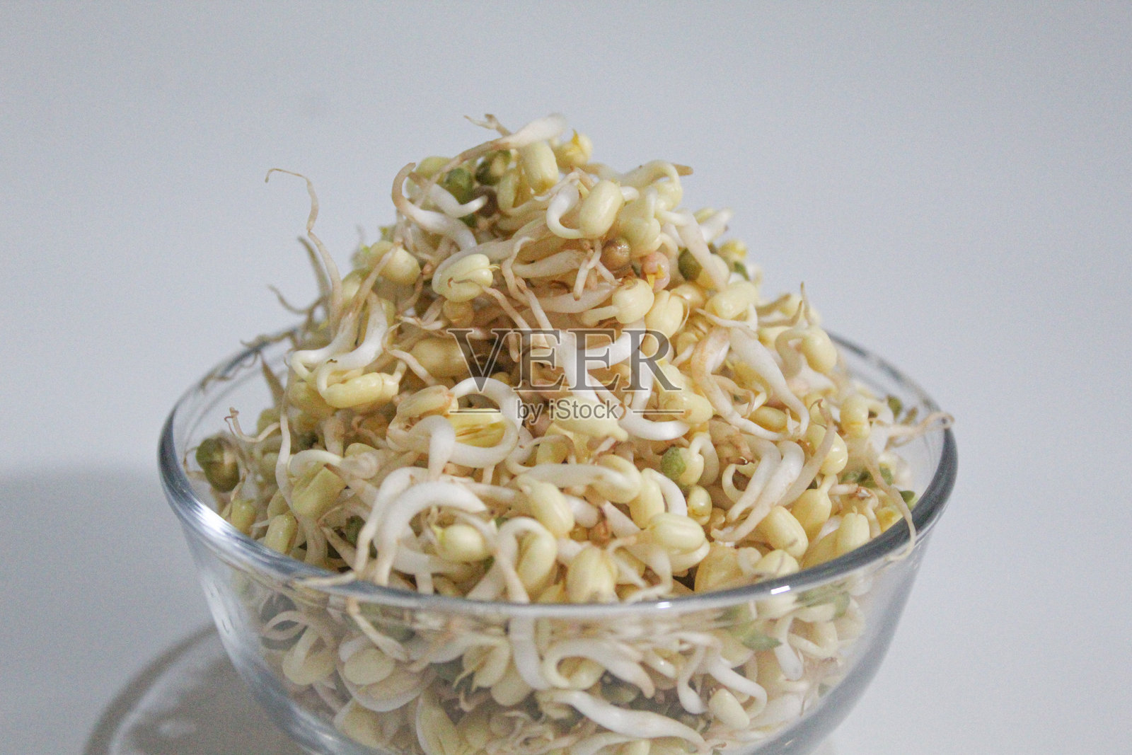 绿豆芽,放在透明碗中,背景为白色。新鲜且未烹饪。照片摄影图片